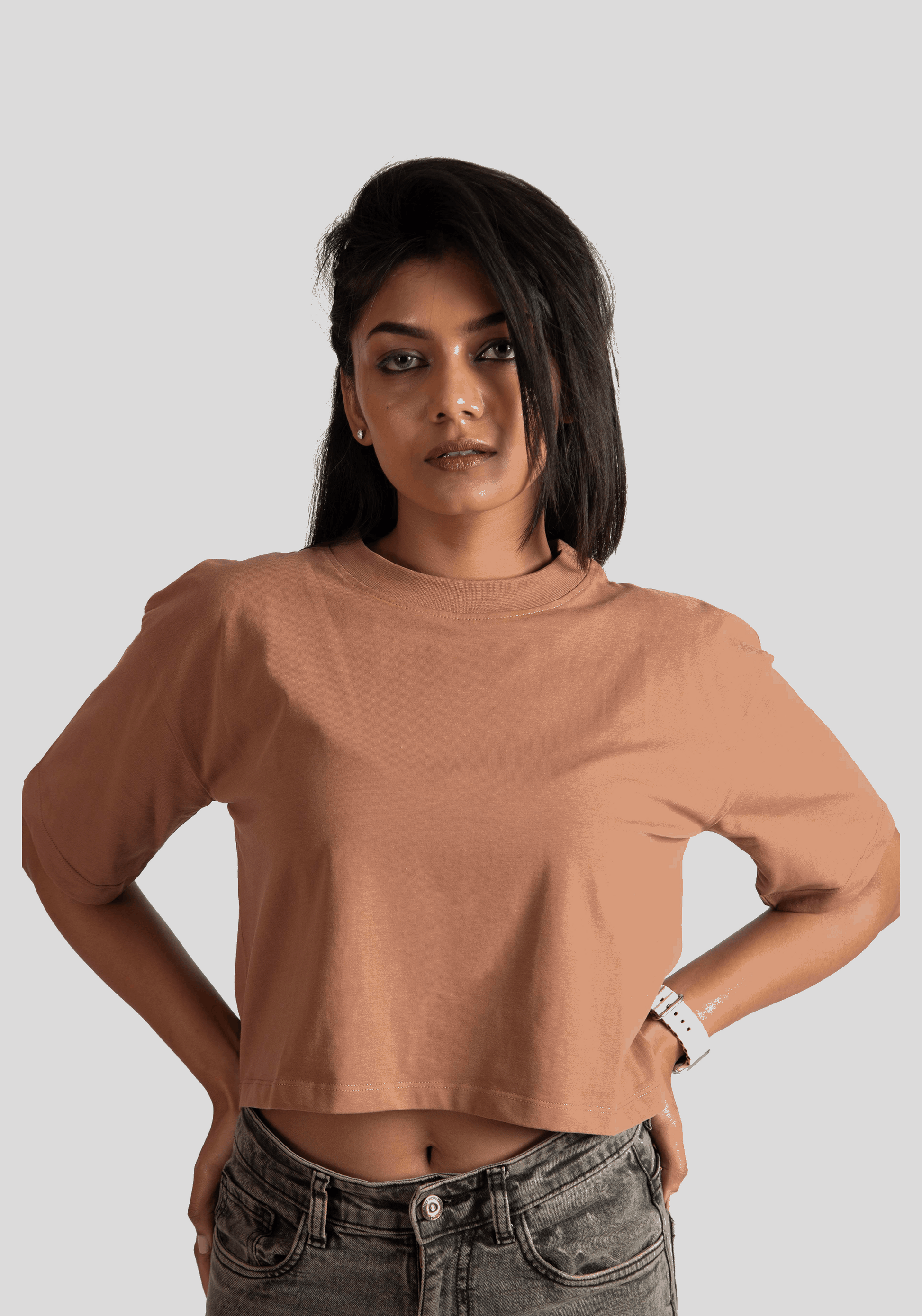 Woman wearing Stylera mocha oversized crop top paired with denim jeans against a plain background