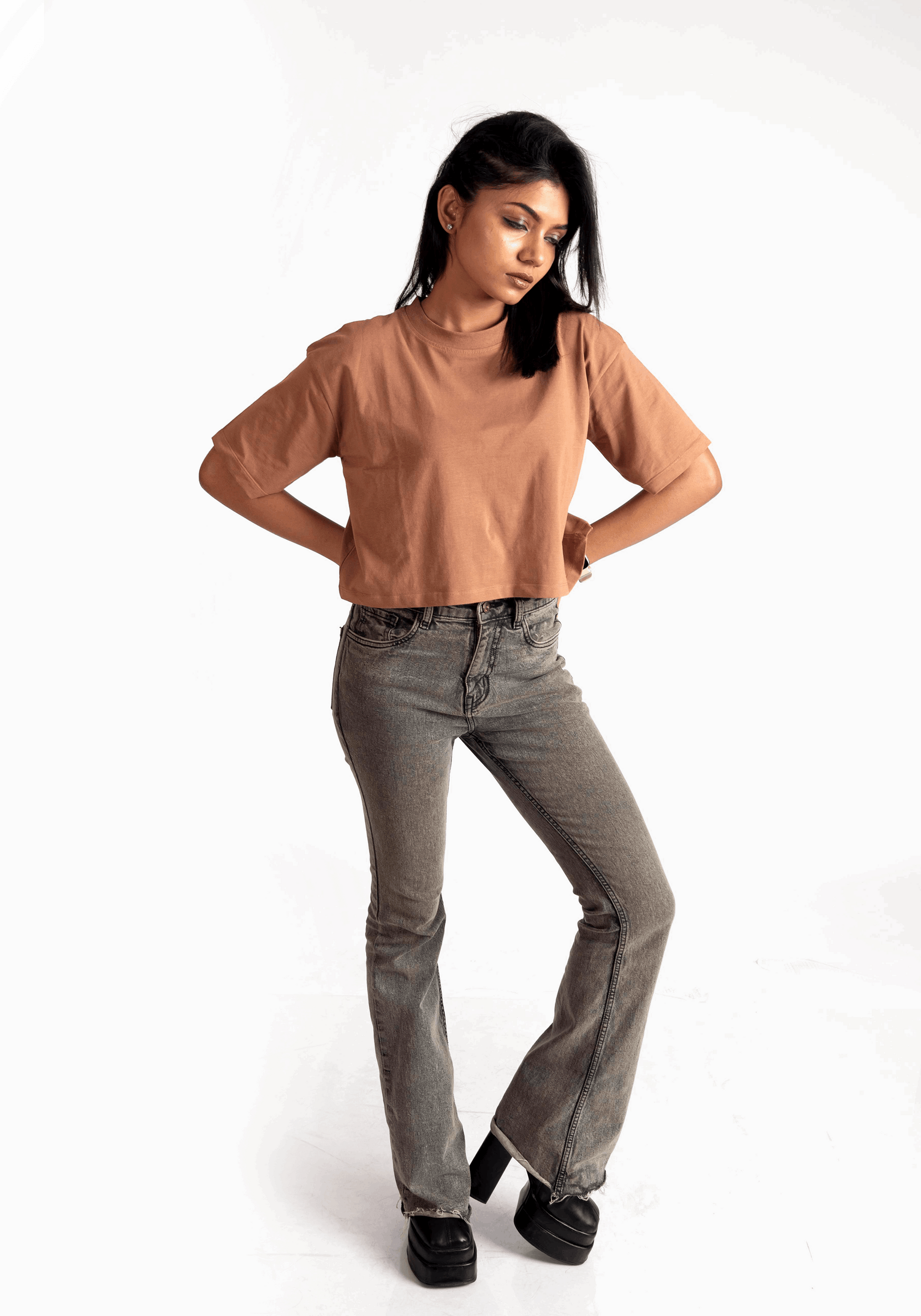 Woman wearing mocha oversized crop top from Stylera paired with gray jeans and black shoes