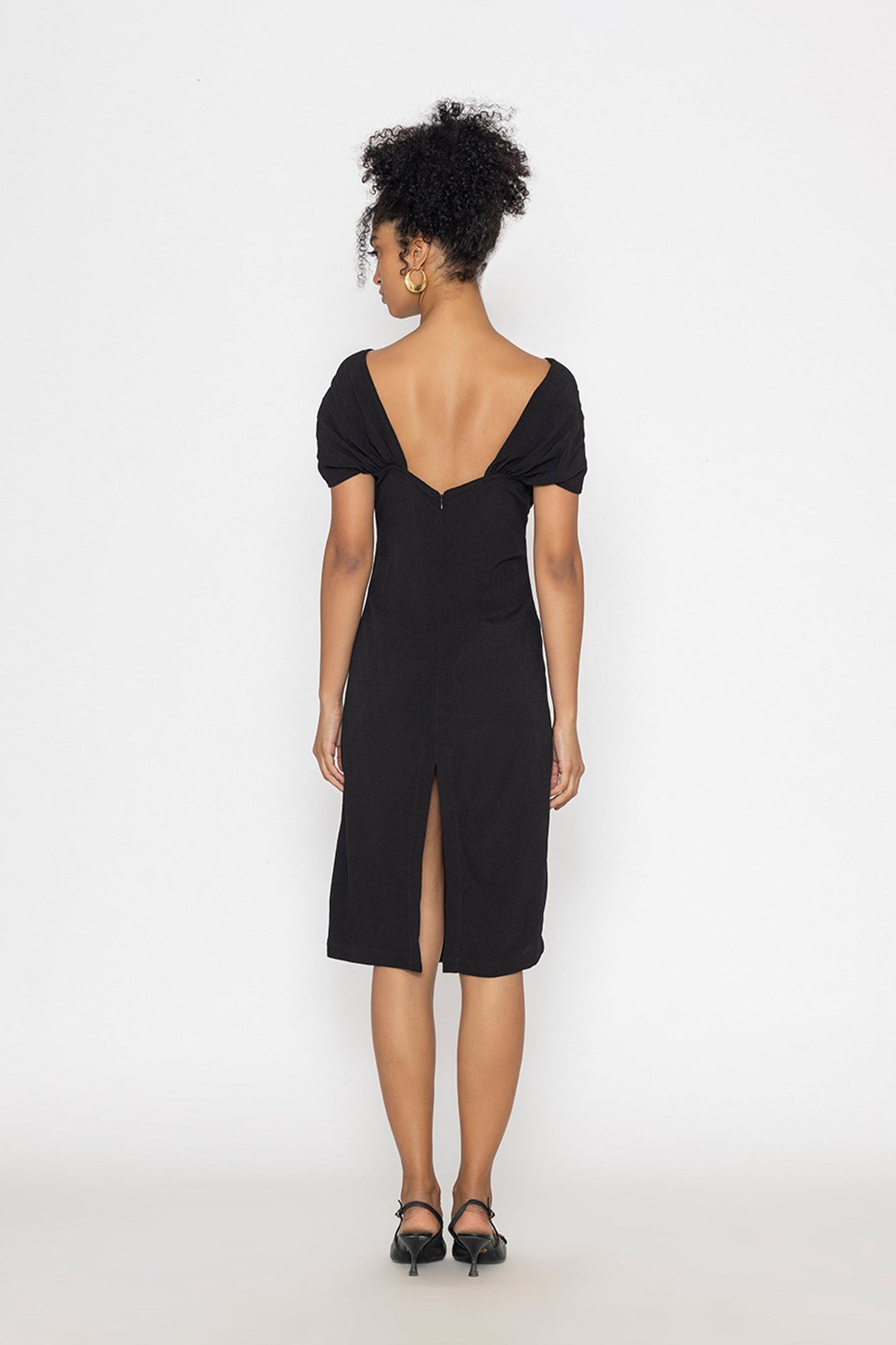 Back view of woman wearing black moonlit tide cocktail dress by Stylera with low back and slit