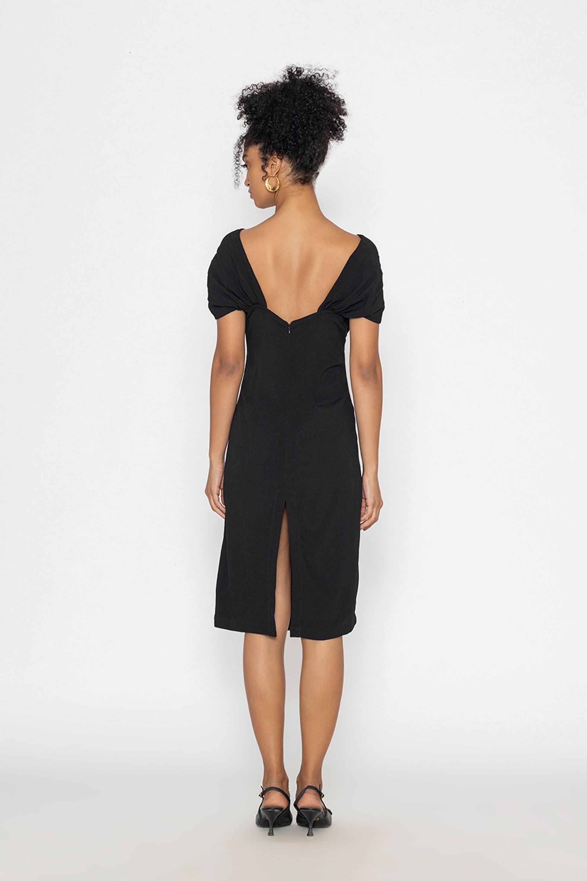 Back view of woman wearing black moonlit tide cocktail dress by Stylera with low back and slit