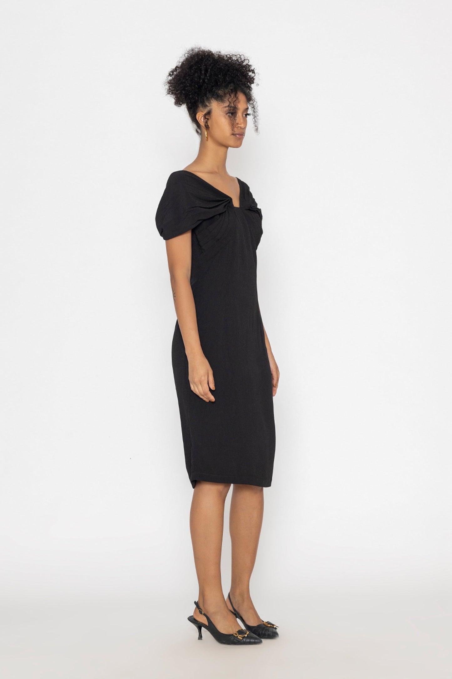 Stylera moonlit tide cocktail dress in black midi length with twisted neckline on model