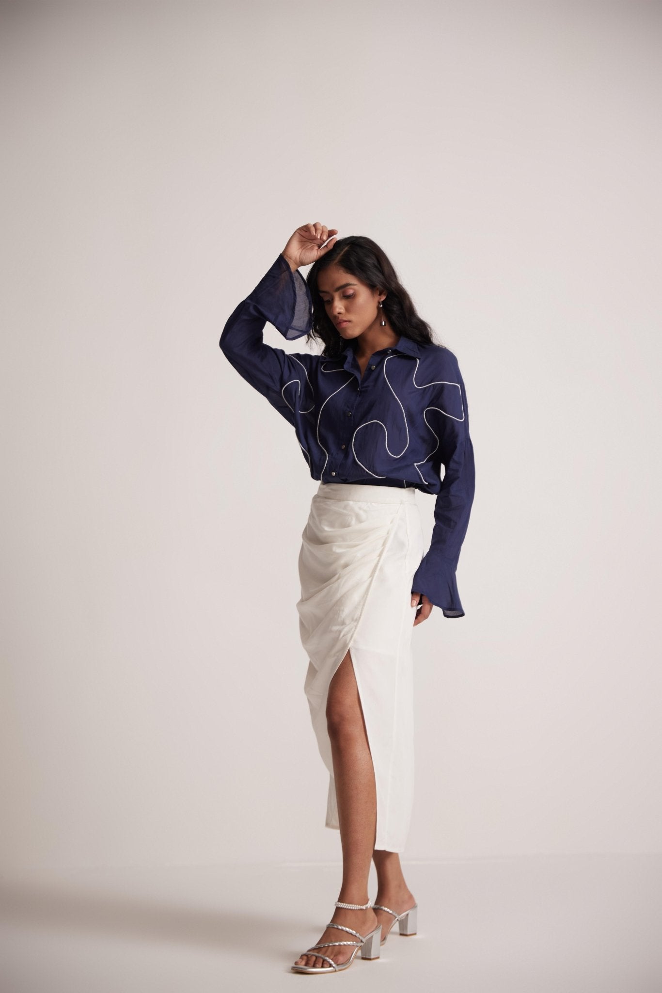 Model wearing a navy blue oversized cotton shirt with embroidery by Stylera paired with a white skirt