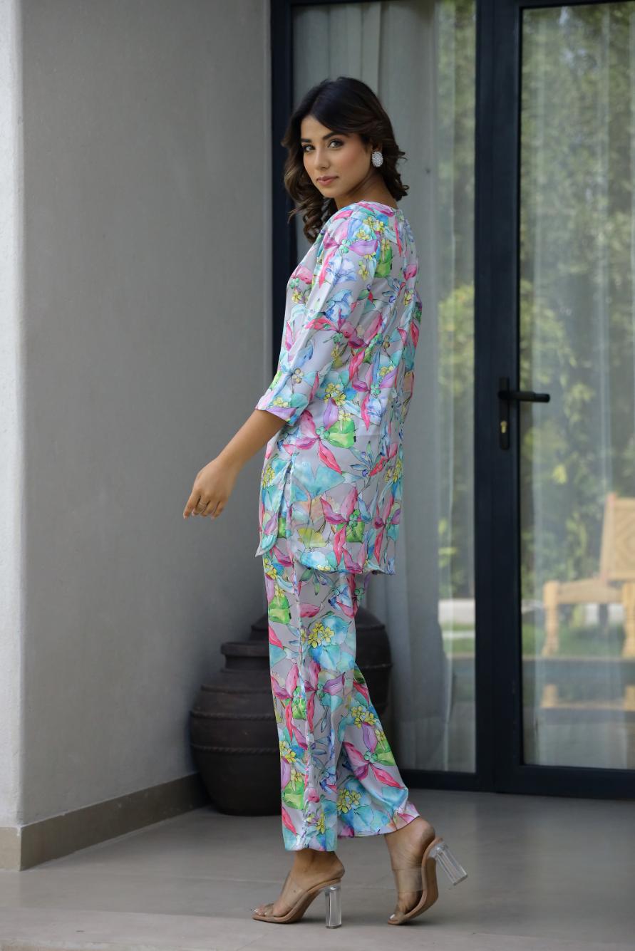 Woman modeling a pastel floral satin pajama set with colorful butterfly design and relaxed fit