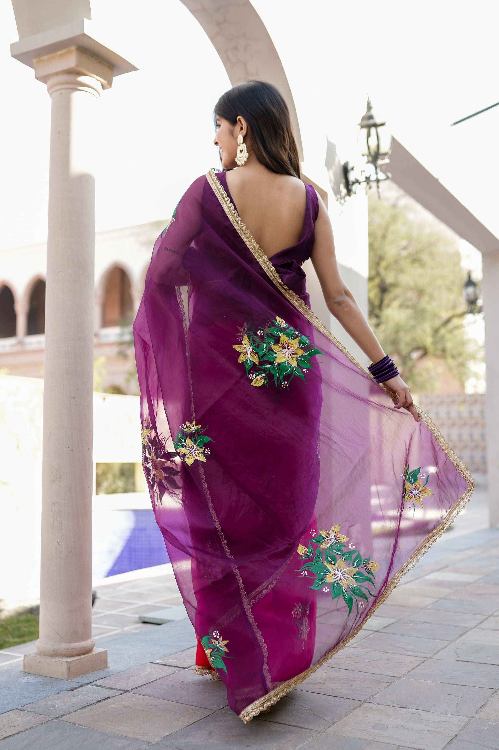Elegant red and purple saree with handwork, featuring floral embroidery and a rich fabric drape