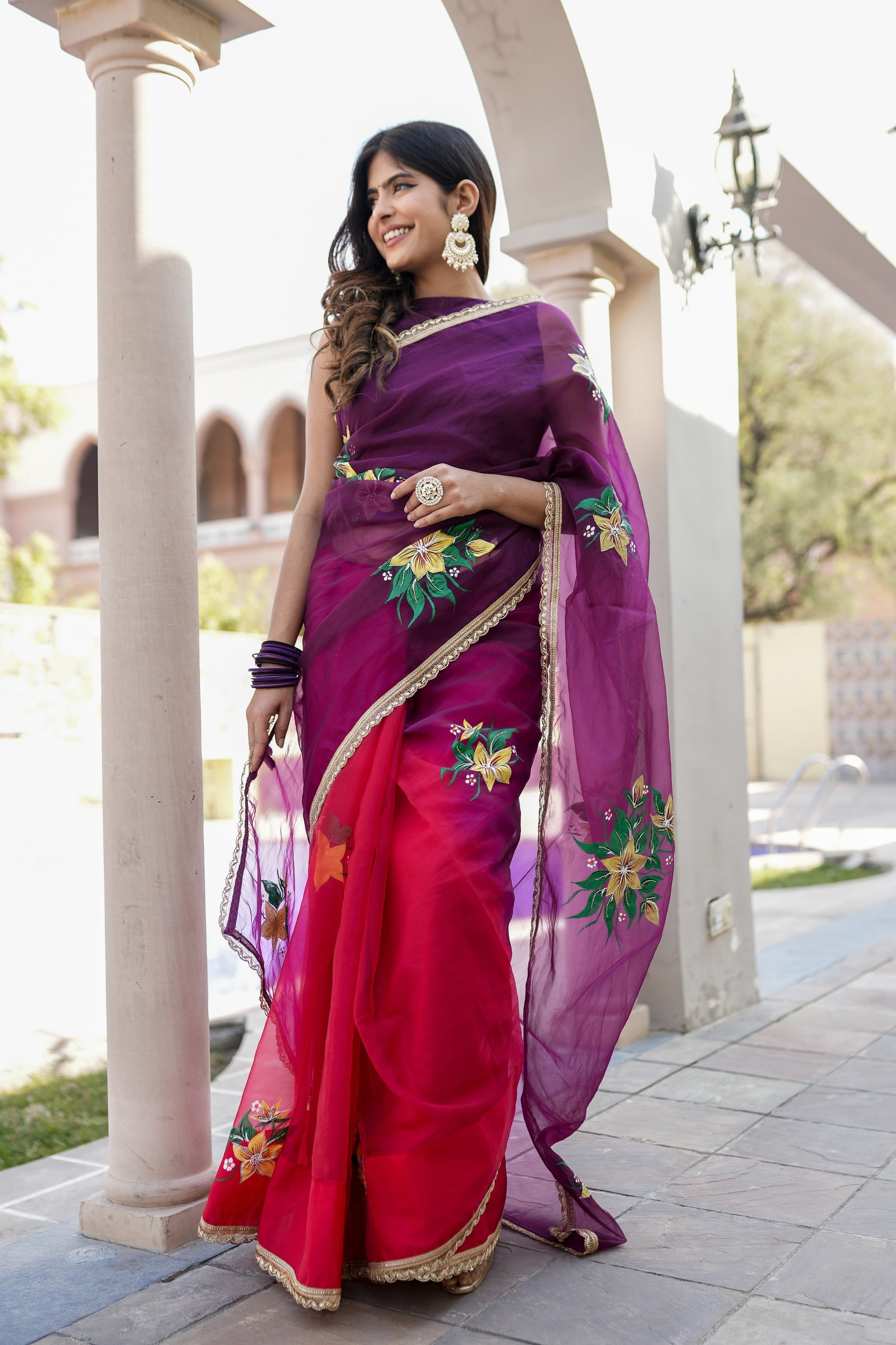 Elegant red and purple saree with handwork, featuring floral designs and a graceful drape