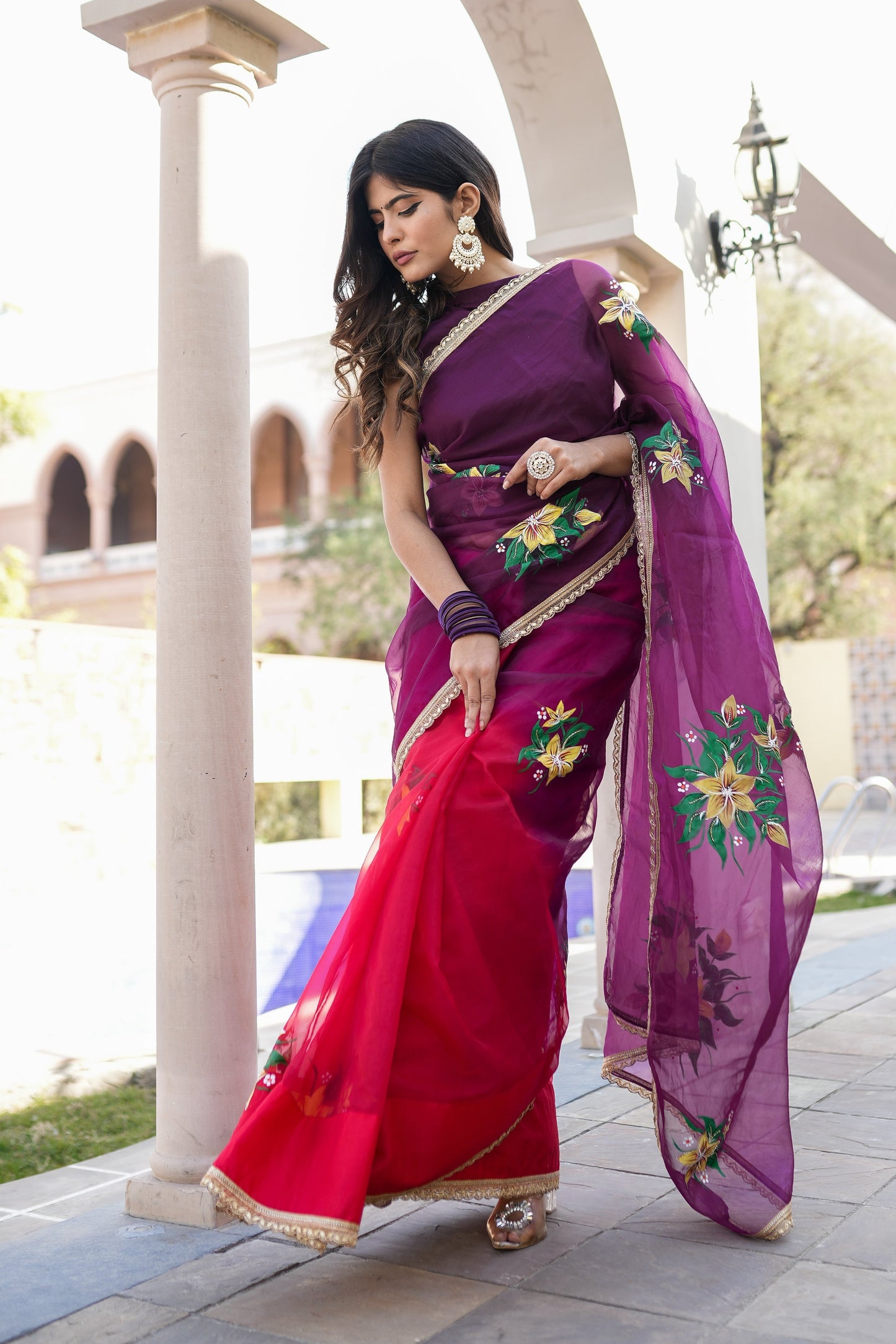 Elegant red and purple saree with handwork displayed by a model outdoors