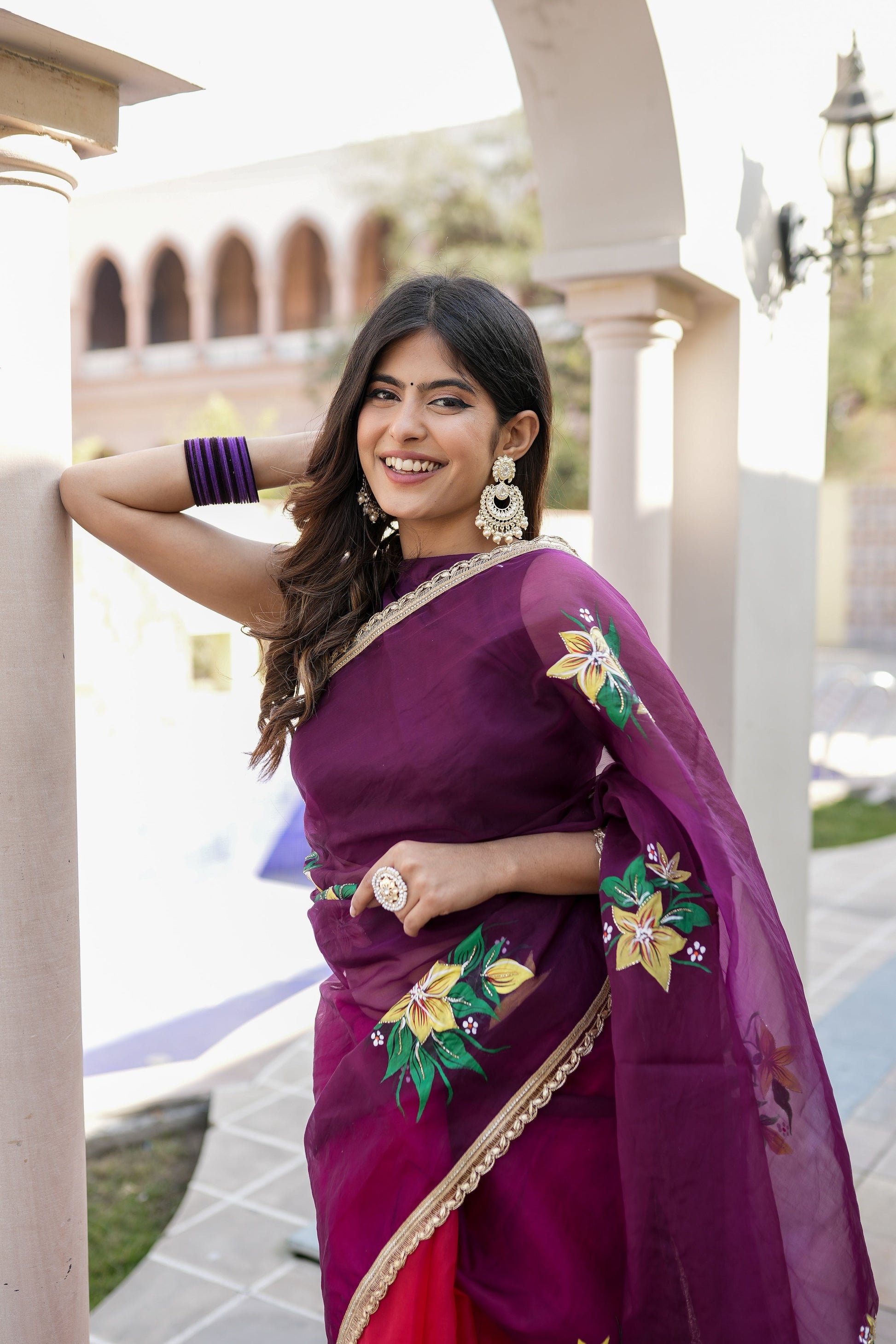Beautiful red and purple saree with handwork, featuring floral designs and elegant accessories