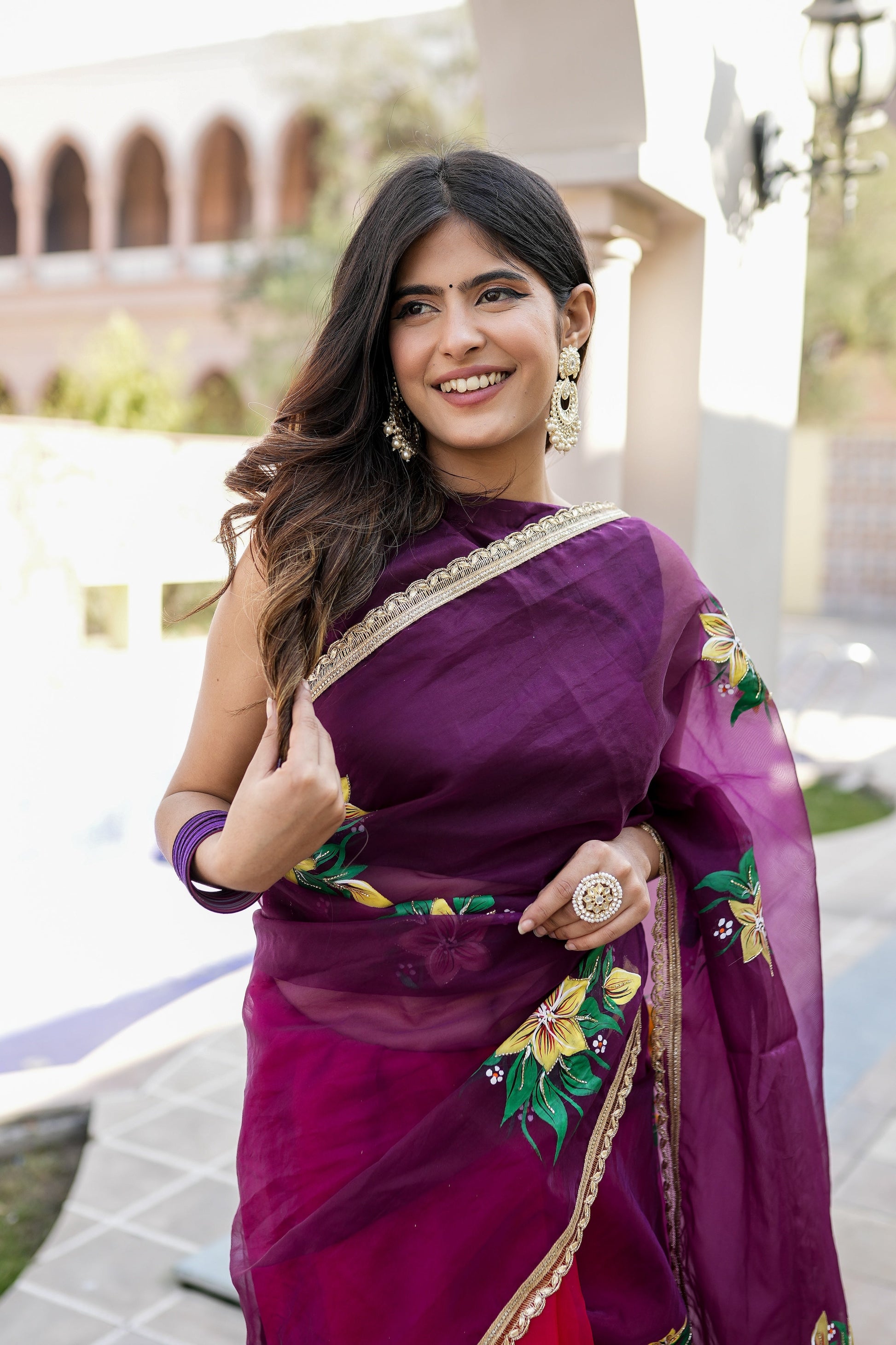Beautiful red and purple saree with handwork worn elegantly, featuring floral design and accessories