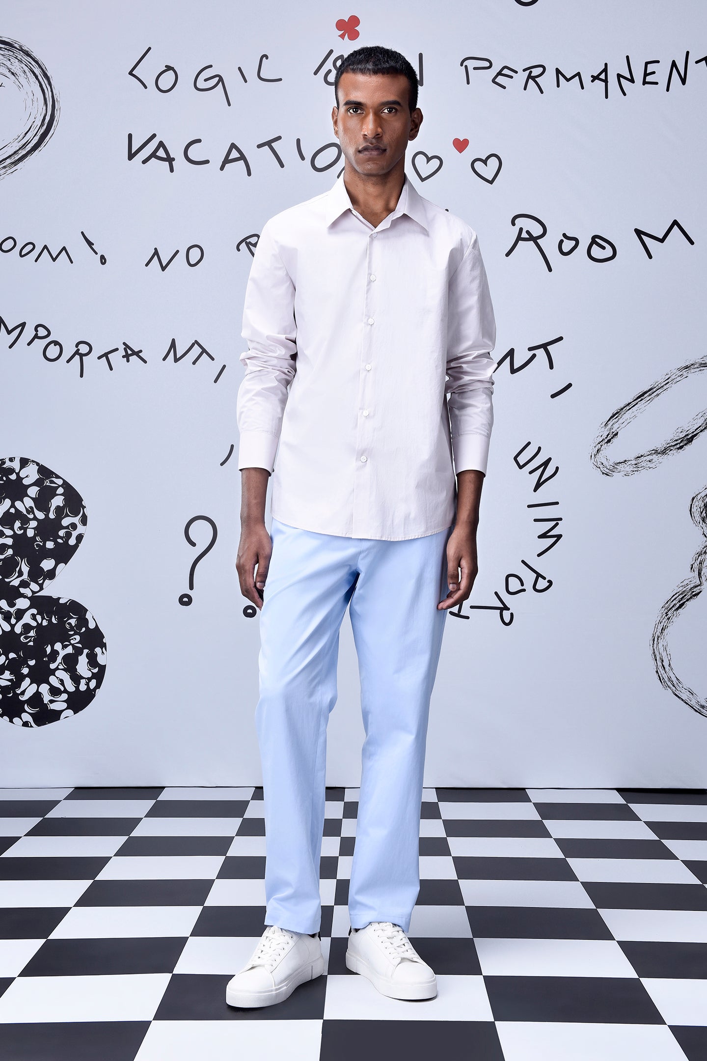 Male model wearing a pale pink button down regular fit men's shirt cotton with light blue trousers and white sneakers