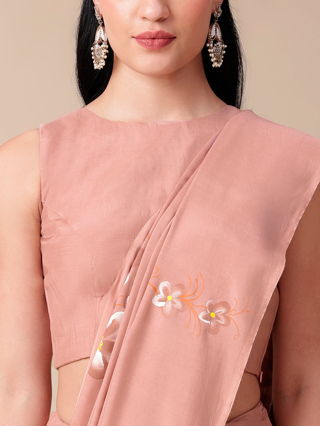 Model wearing a soft cotton saree with floral design in pastel pink, paired with elegant earrings