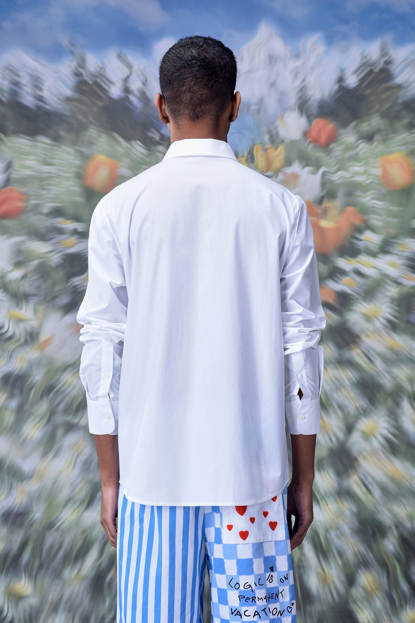 Back view of a man wearing a stylish white shirt for men Stylera standing in a blurred floral background