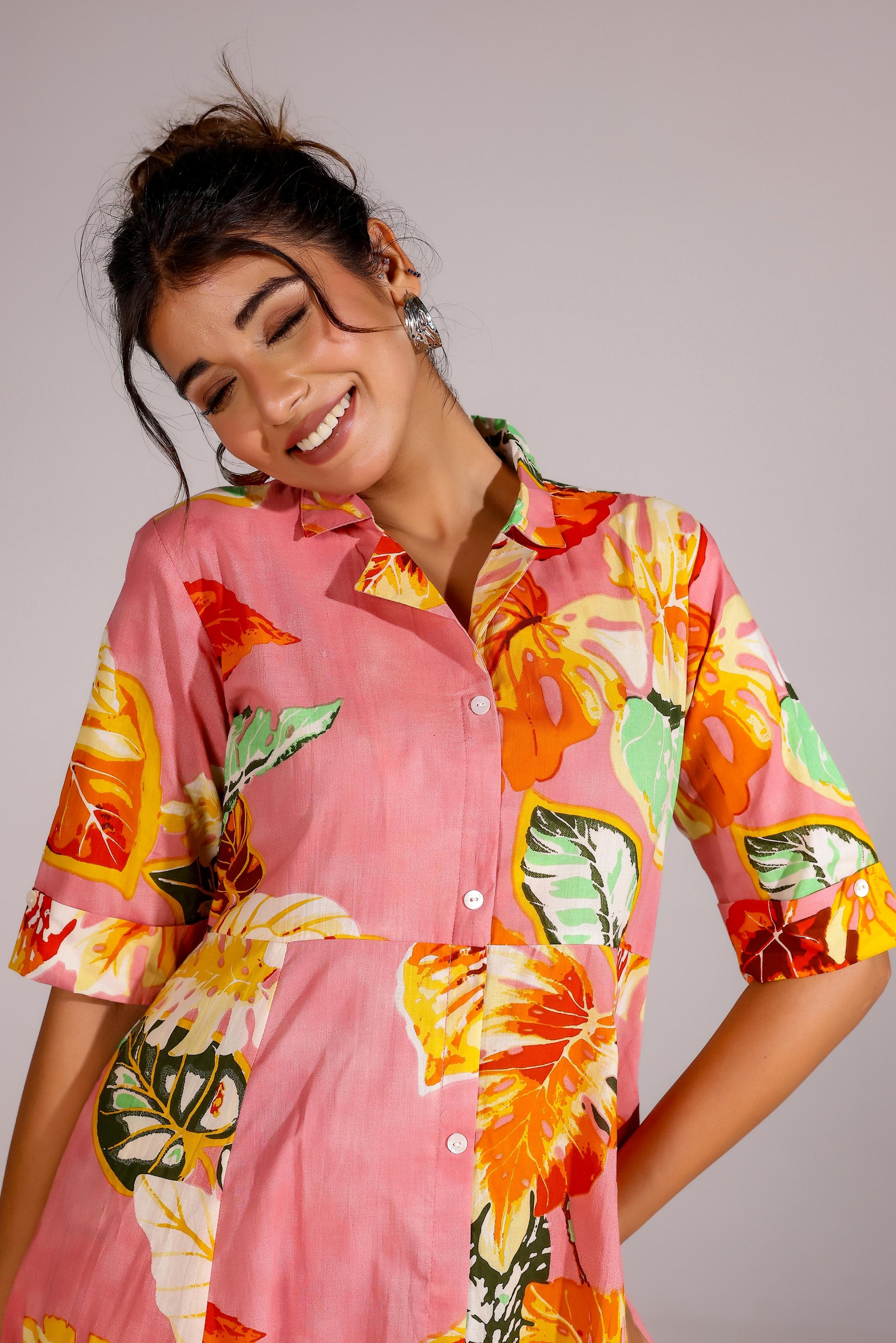 Woman wearing a summer pink cotton dress with vibrant floral patterns and a button-up design