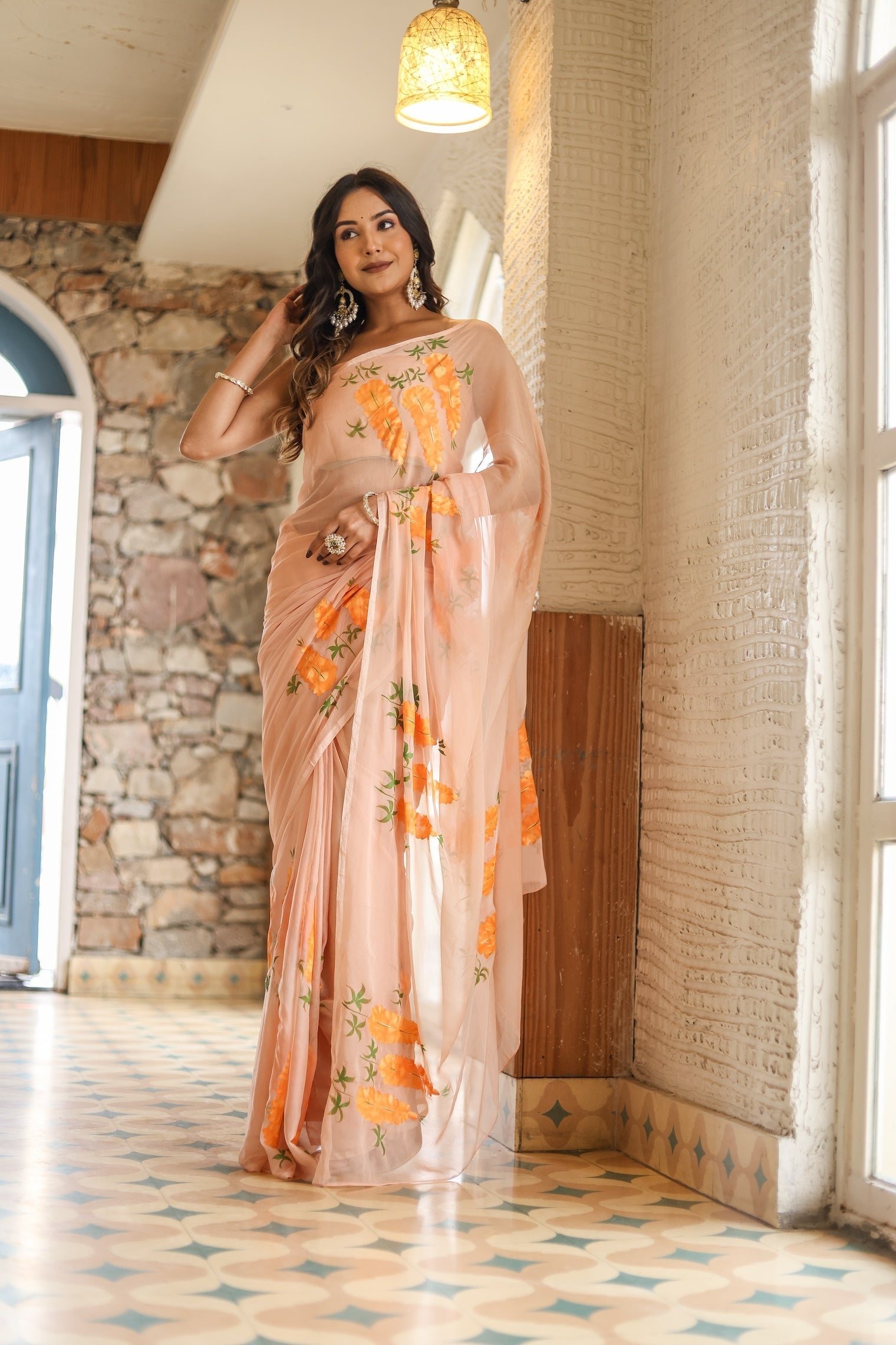 Elegant woman wearing a trendy peach saree with floral design, showcasing vibrant patterns in a stylish setting