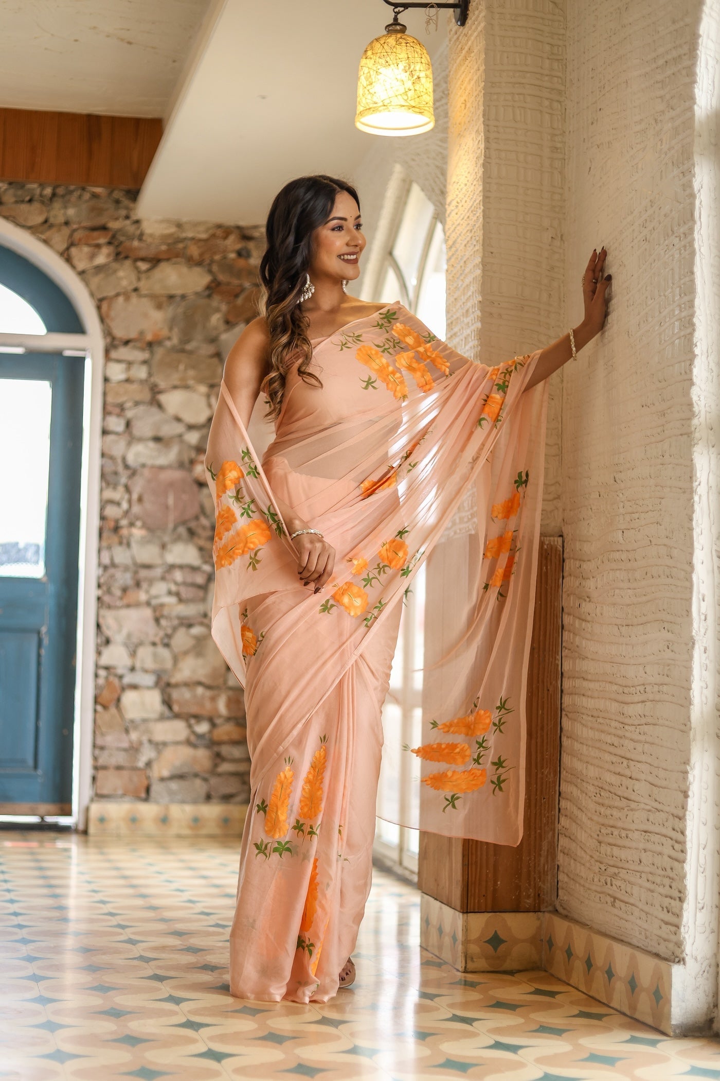 Elegant woman wearing a trendy peach saree with floral design, posing gracefully indoors