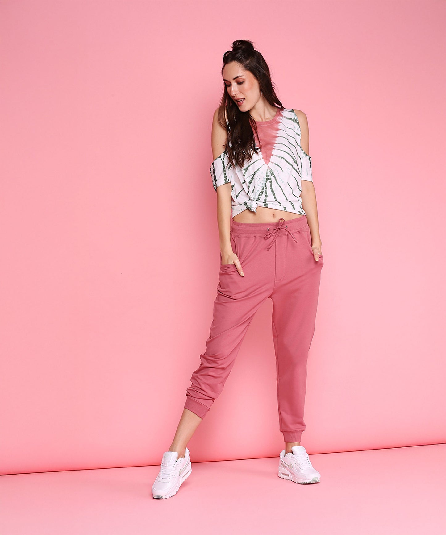 Trendy pink sweatpants with a relaxed fit, styled with a casual crop top and white sneakers