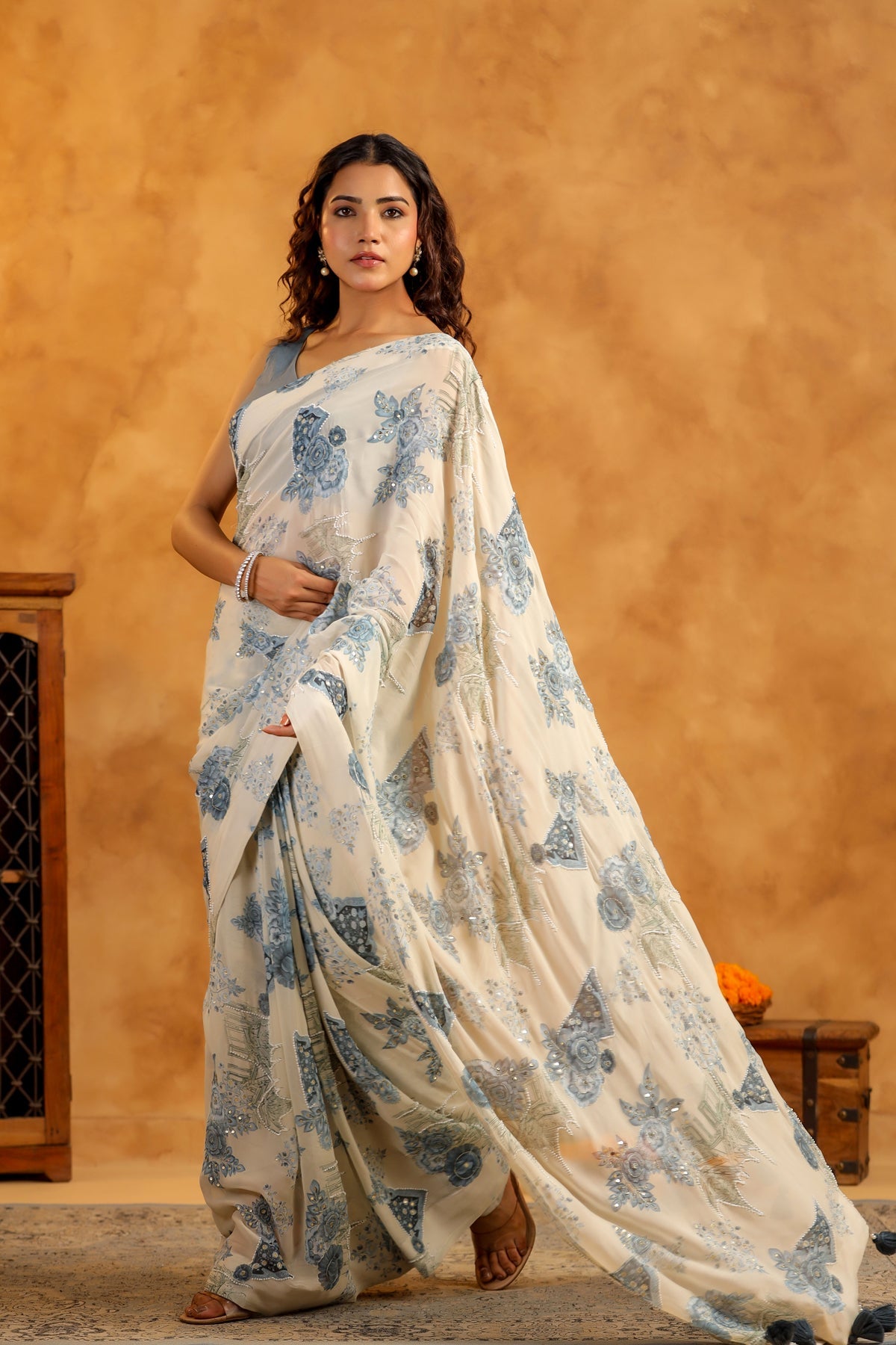 Model wearing Stylera trendy saree with blouse set cream saree with blue floral prints full length drape