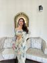 Woman modeling trendy saree with blouse set cream and blue floral print in living room with decorative mirror
