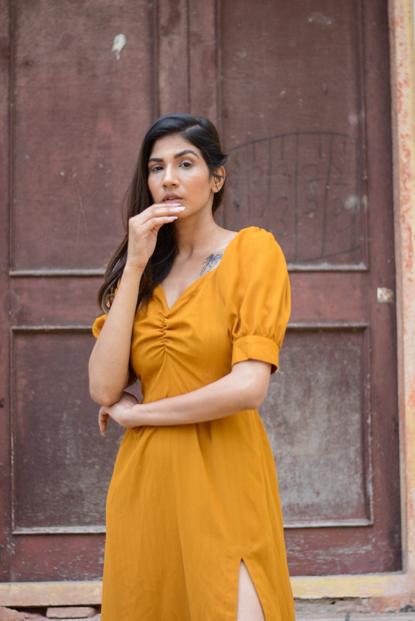 Model wearing a trendy yellow slit midi dress with puff sleeves and a flattering neckline