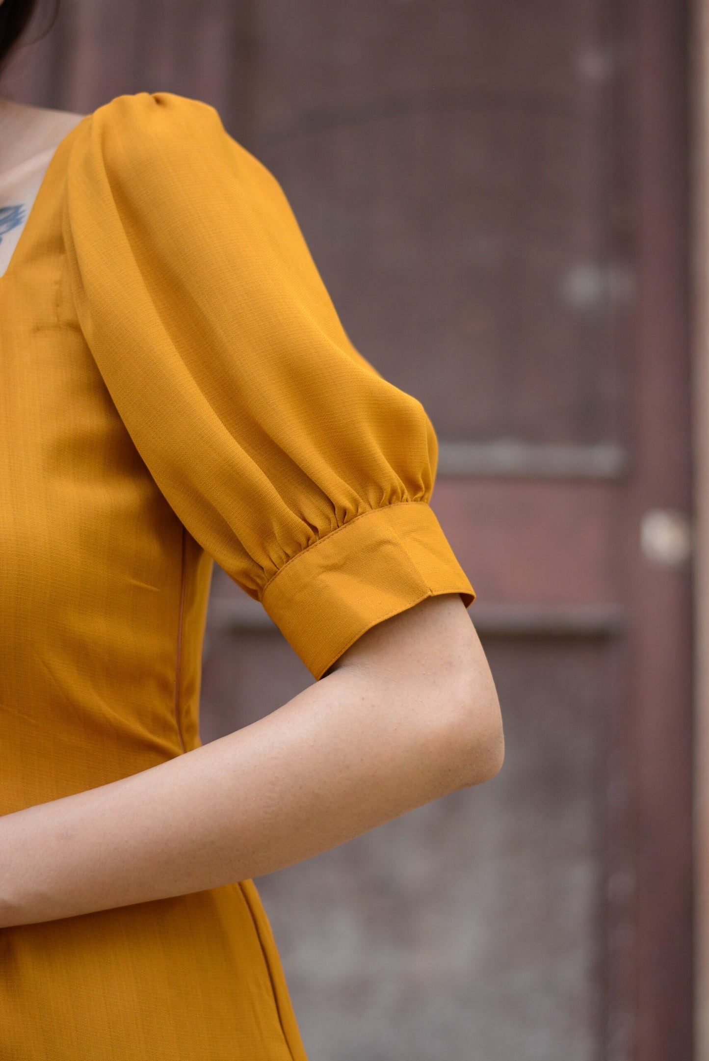 Detail of a trendy yellow slit midi dress featuring puff sleeves and a stylish neckline