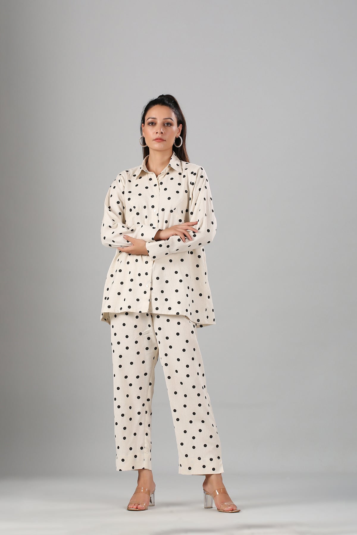 Woman wearing Stylera two piece outfit polka dots cream collared button shirt and matching straight pants with heels