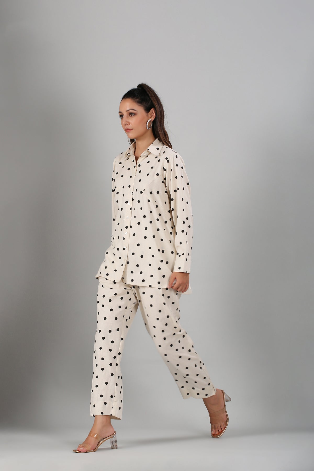 Stylera model wearing two piece outfit polka dots cream button up top and matching trousers with heels