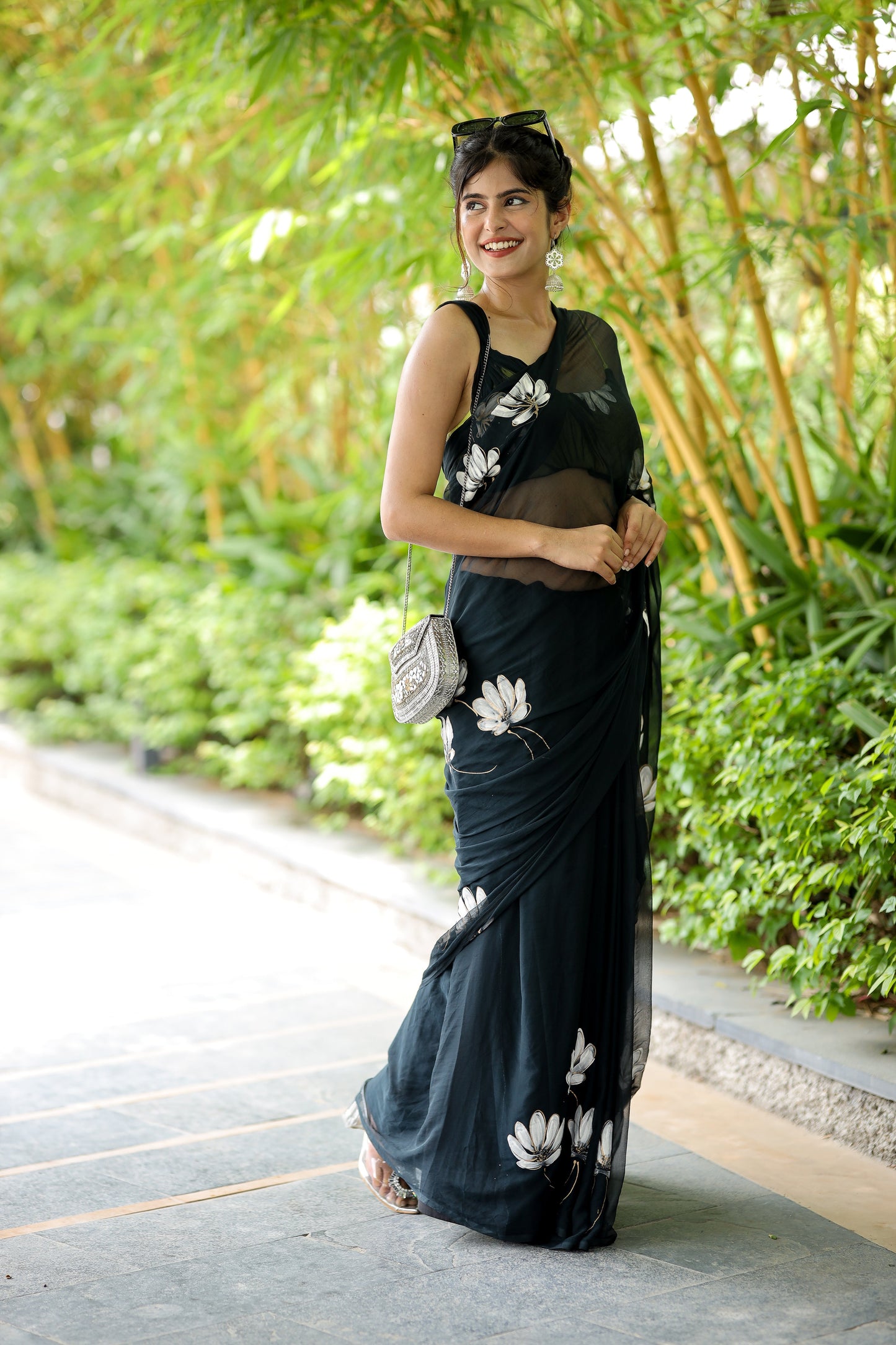 Elegant model wearing a unique black saree for party wear with floral details in a lush garden setting