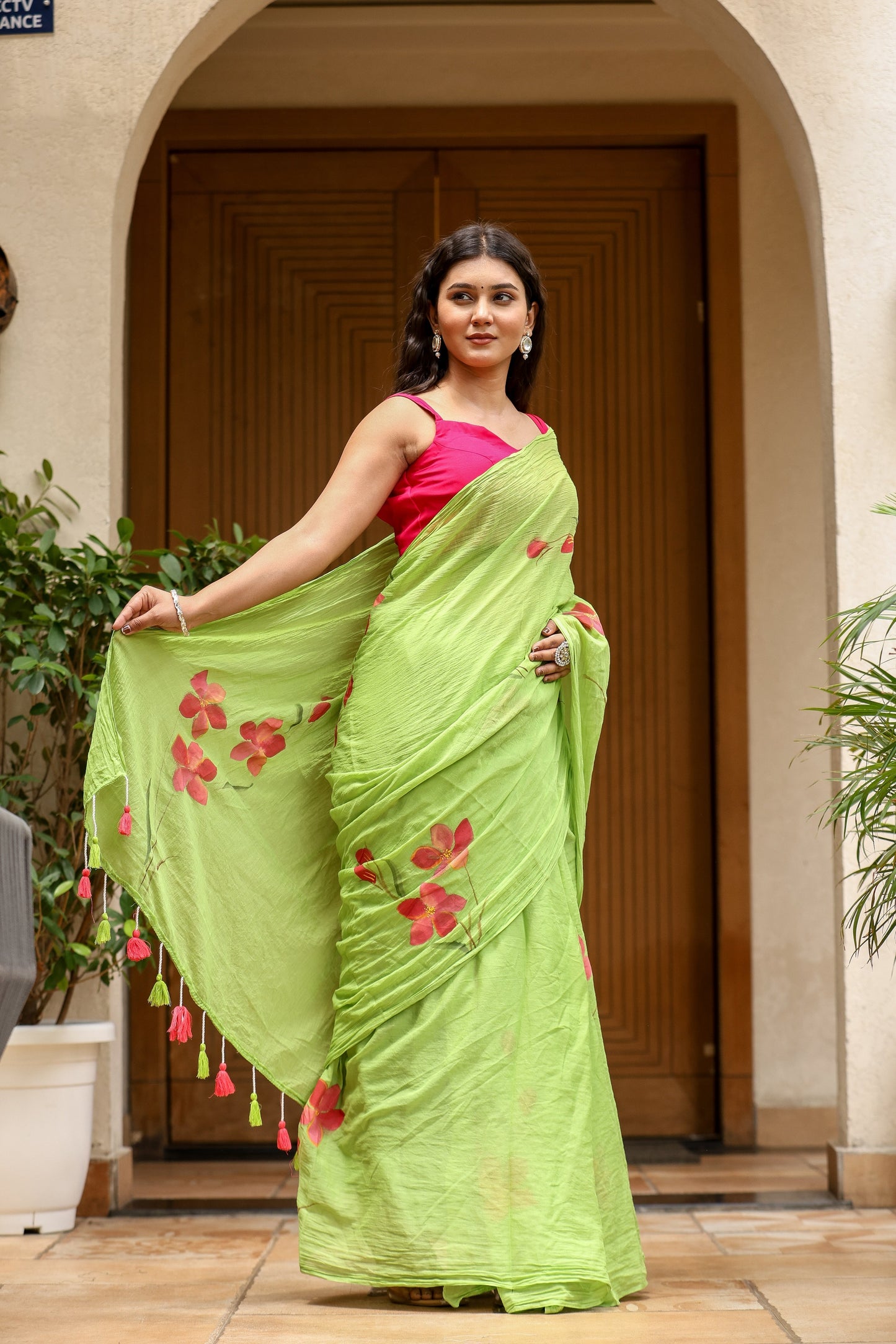 Model draped in a unique designer malmal saree in green with floral embroidery and tassels
