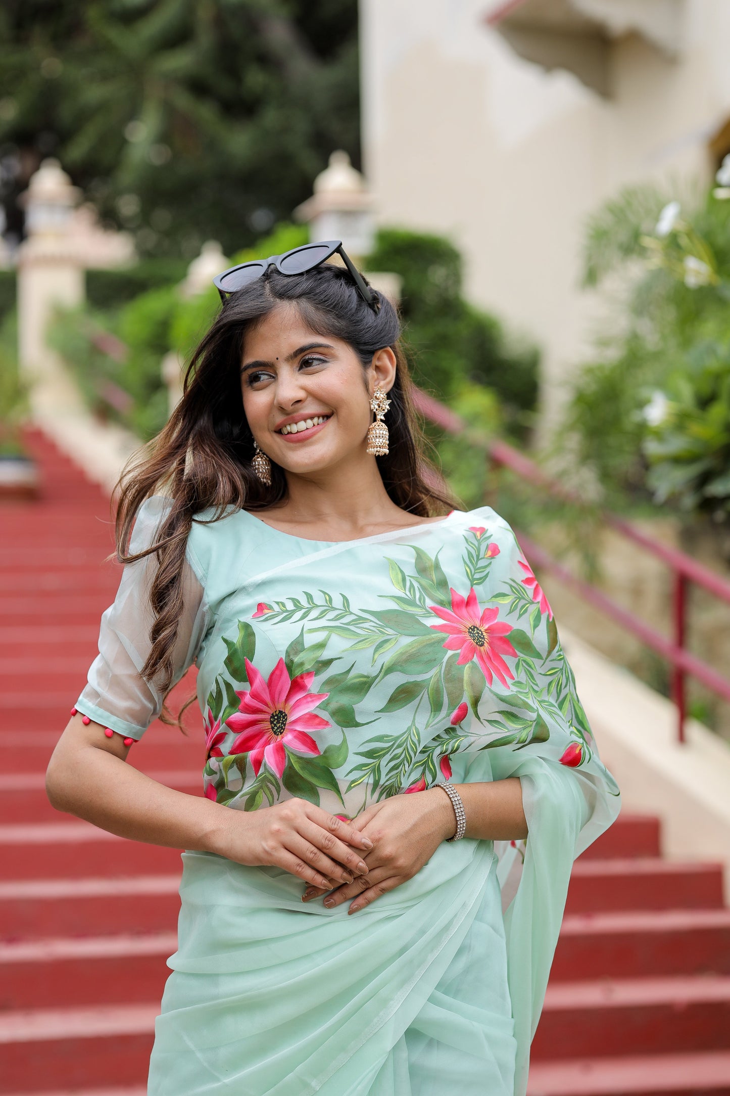 Graceful woman wearing a unique designer organza saree with vibrant floral embroidery outdoors