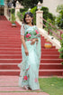 Elegant woman wearing a unique designer organza saree with floral embroidery on a sunny staircase