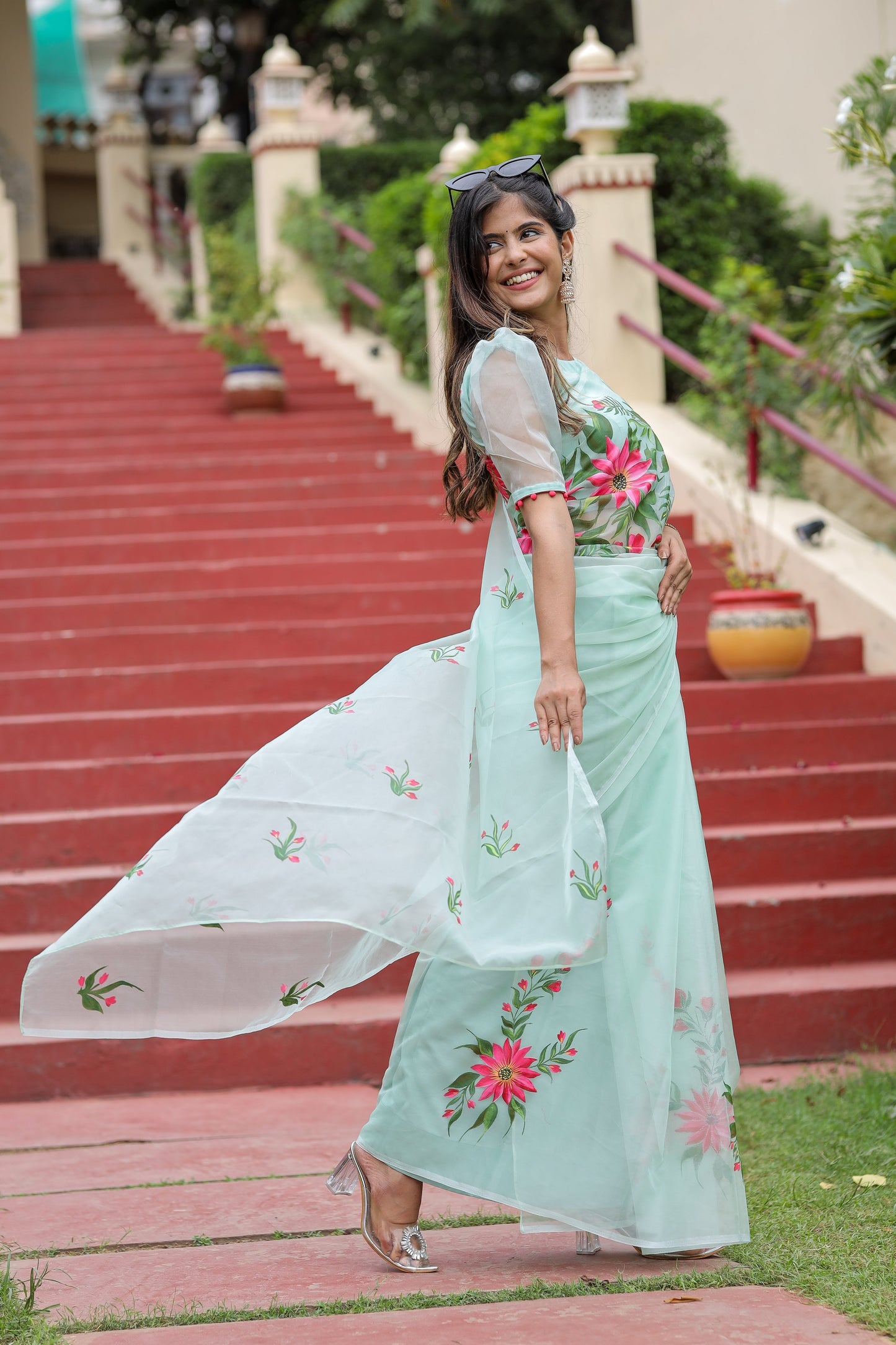 Model showcasing a unique designer organza saree in mint green with floral embroidery and matching blouse