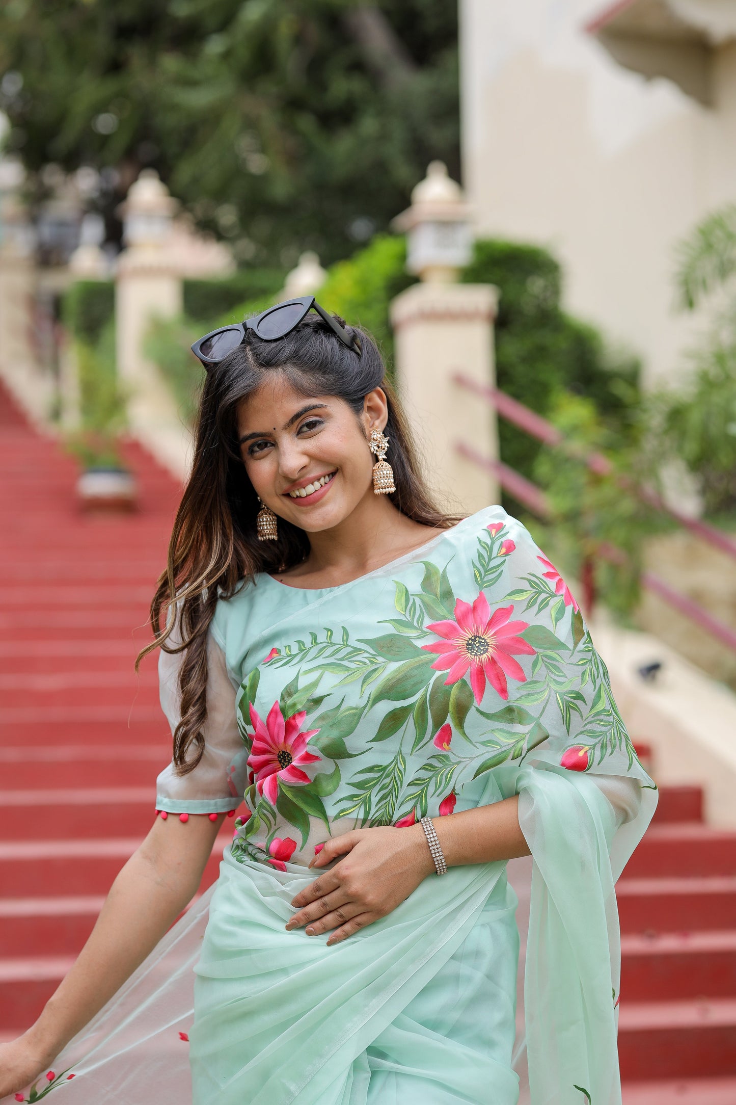 Elegant woman in a unique designer organza saree with floral patterns posing outdoors