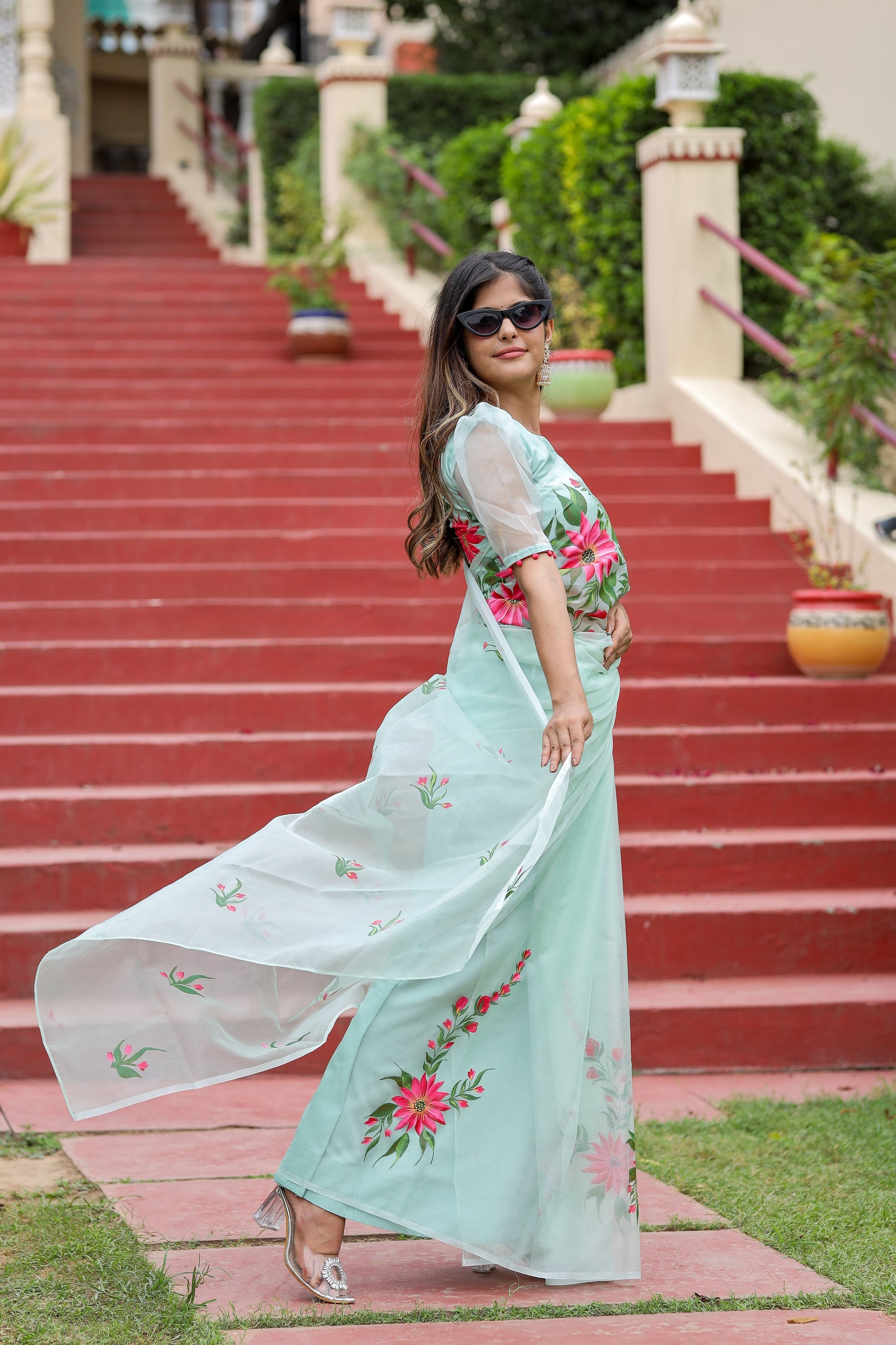 Stylish model wearing a unique designer organza saree with floral embroidery outdoors