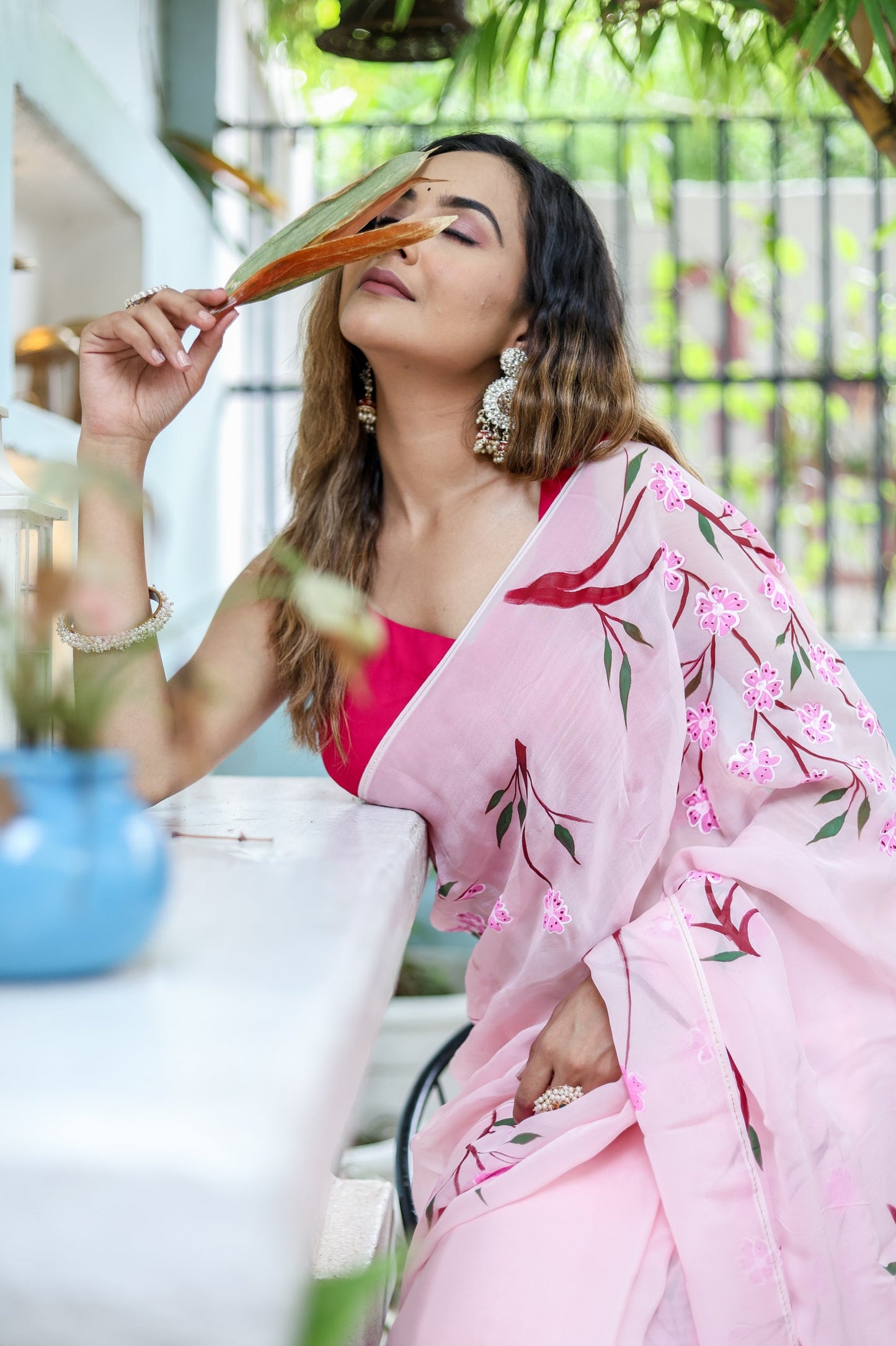 Elegant model wearing a unique handpainted saree for weddings with floral designs and pink hues
