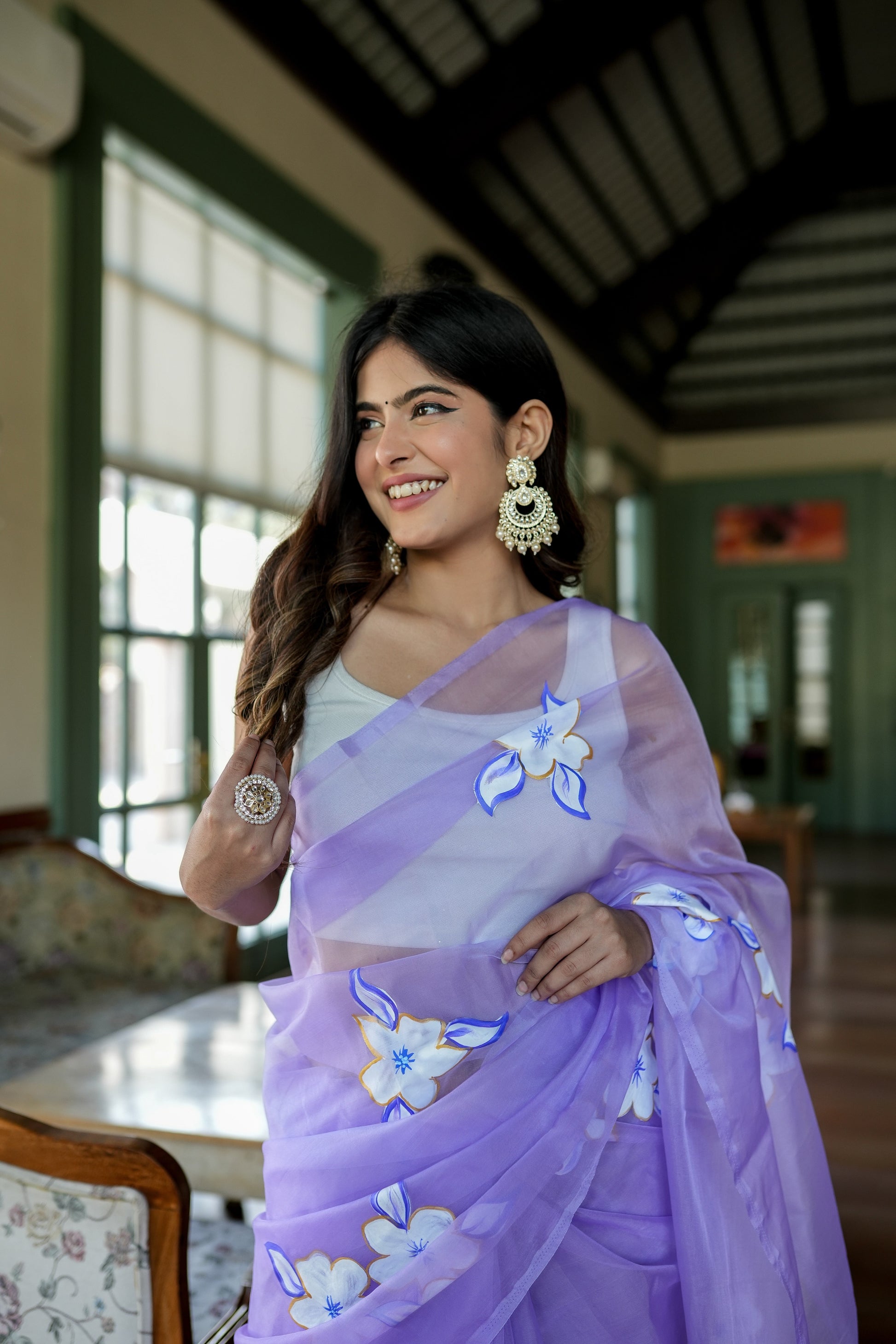 Model wearing a unique organza saree with artwork, featuring floral designs in lavender hues