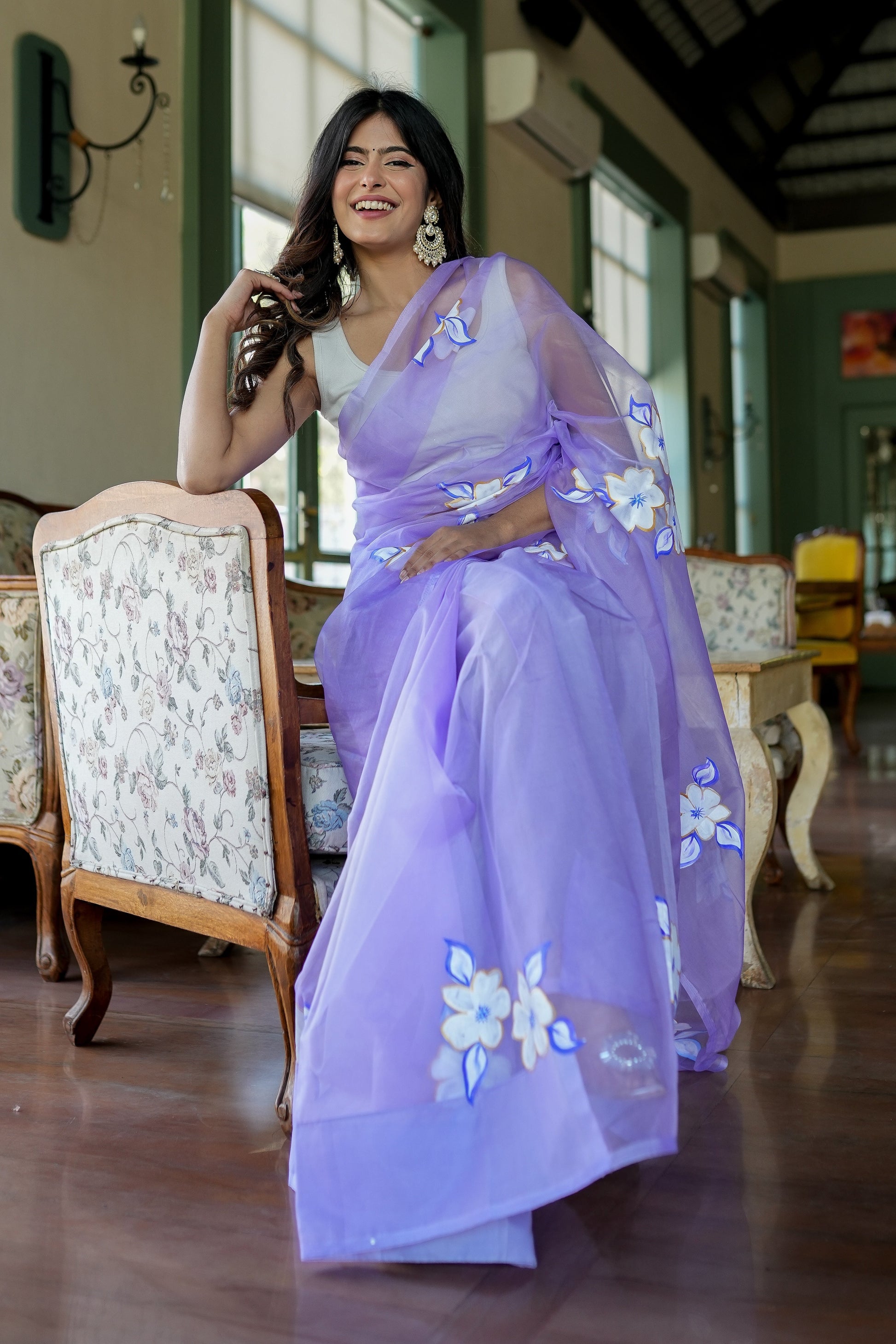 Model wearing a unique organza saree with artwork in lavender, showcasing floral designs and elegance