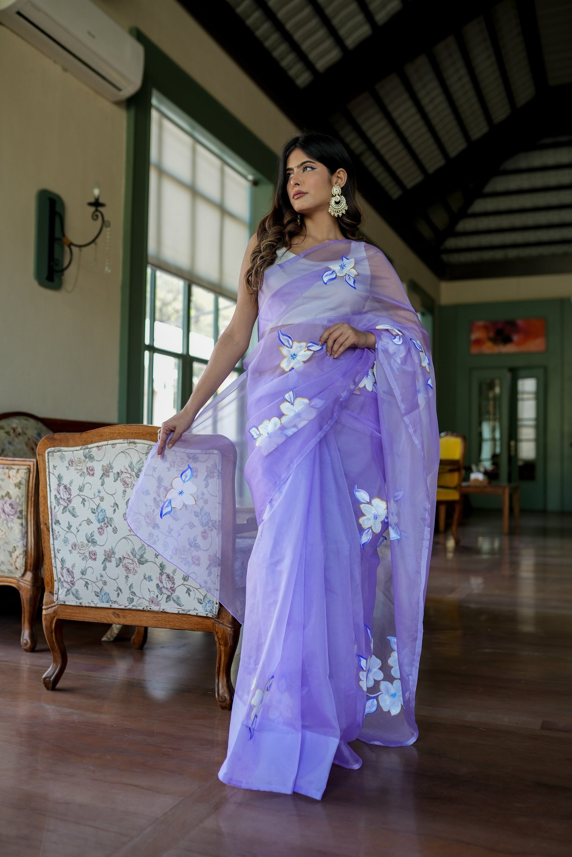 Model wearing a unique organza saree with artwork in lavender, showcasing floral designs and elegant draping.