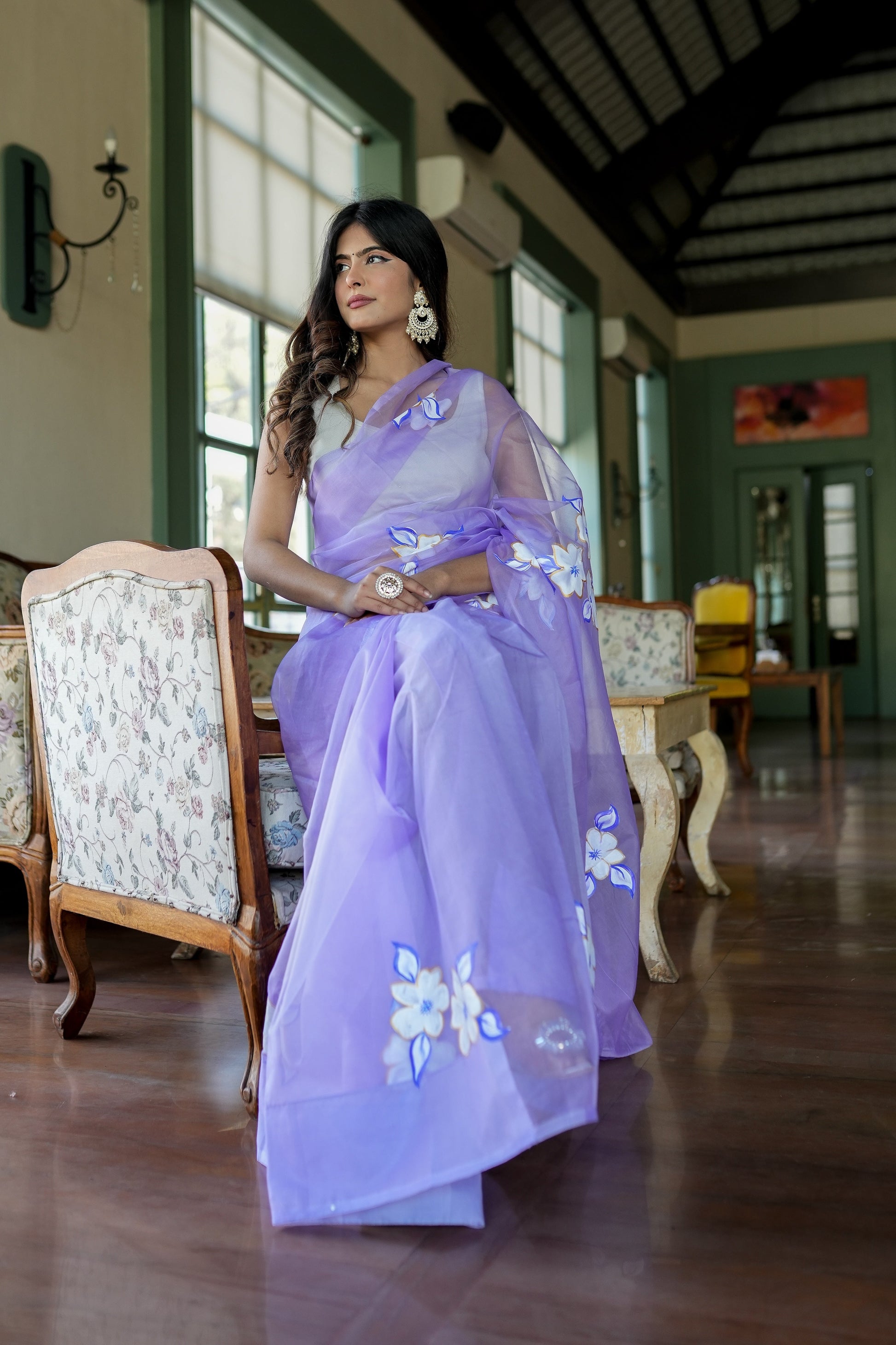 Model wearing a unique organza saree with artwork in lavender color, styled elegantly indoors