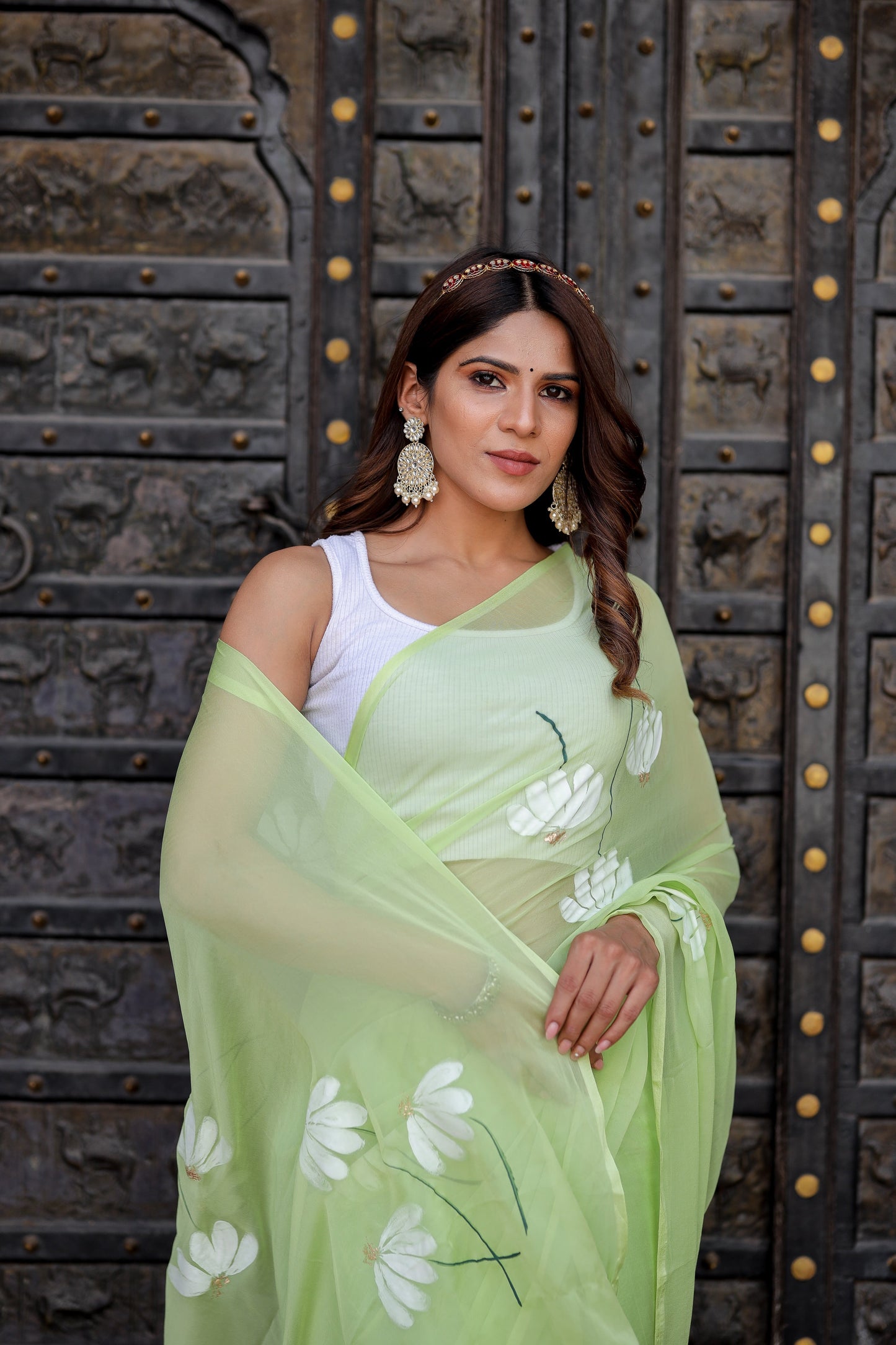 Elegant light green unique saree for wedding guest with floral designs and matching accessories