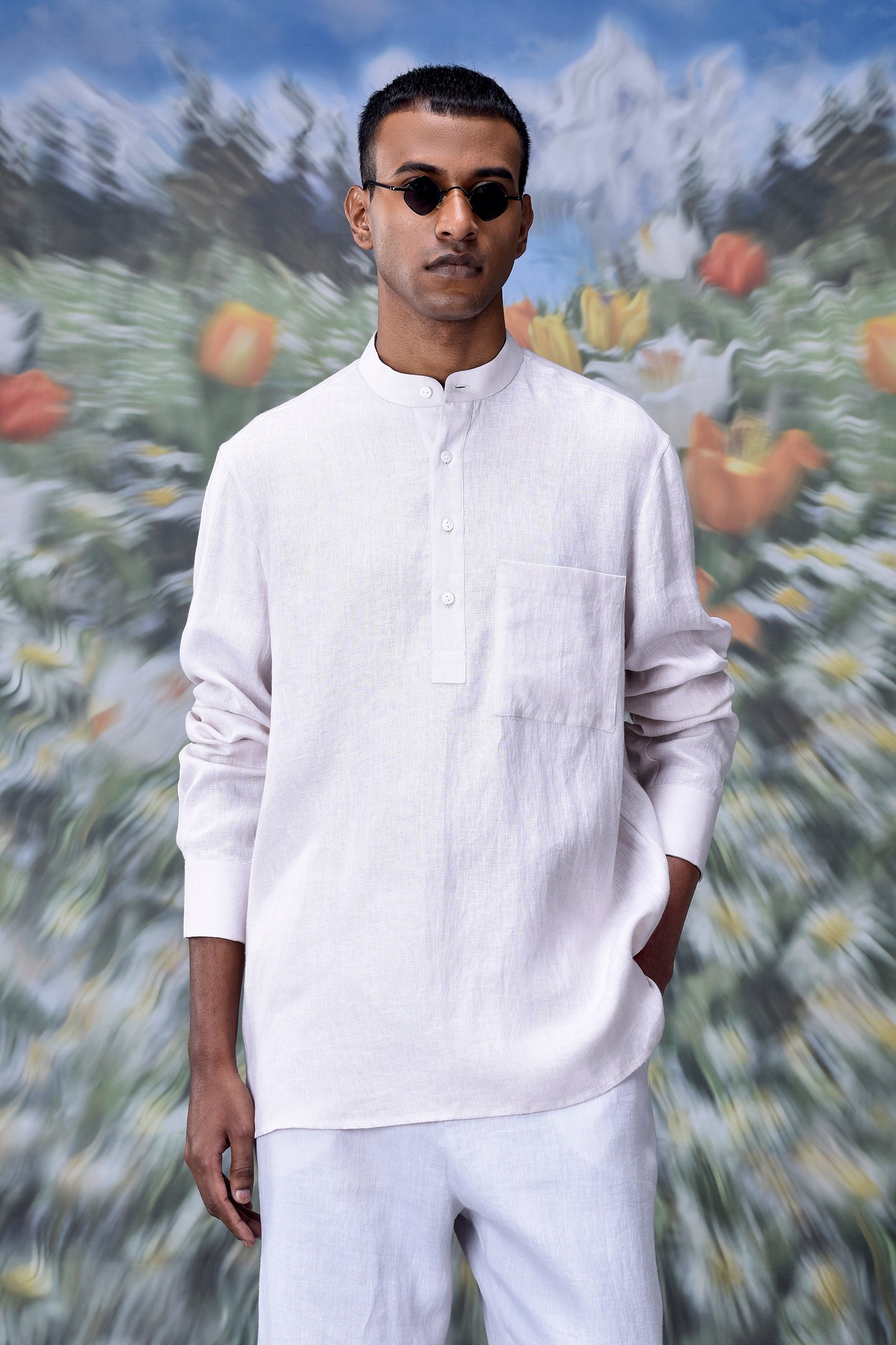Male model wearing a white linen casual shirt for men with mandarin collar chest pocket and round sunglasses