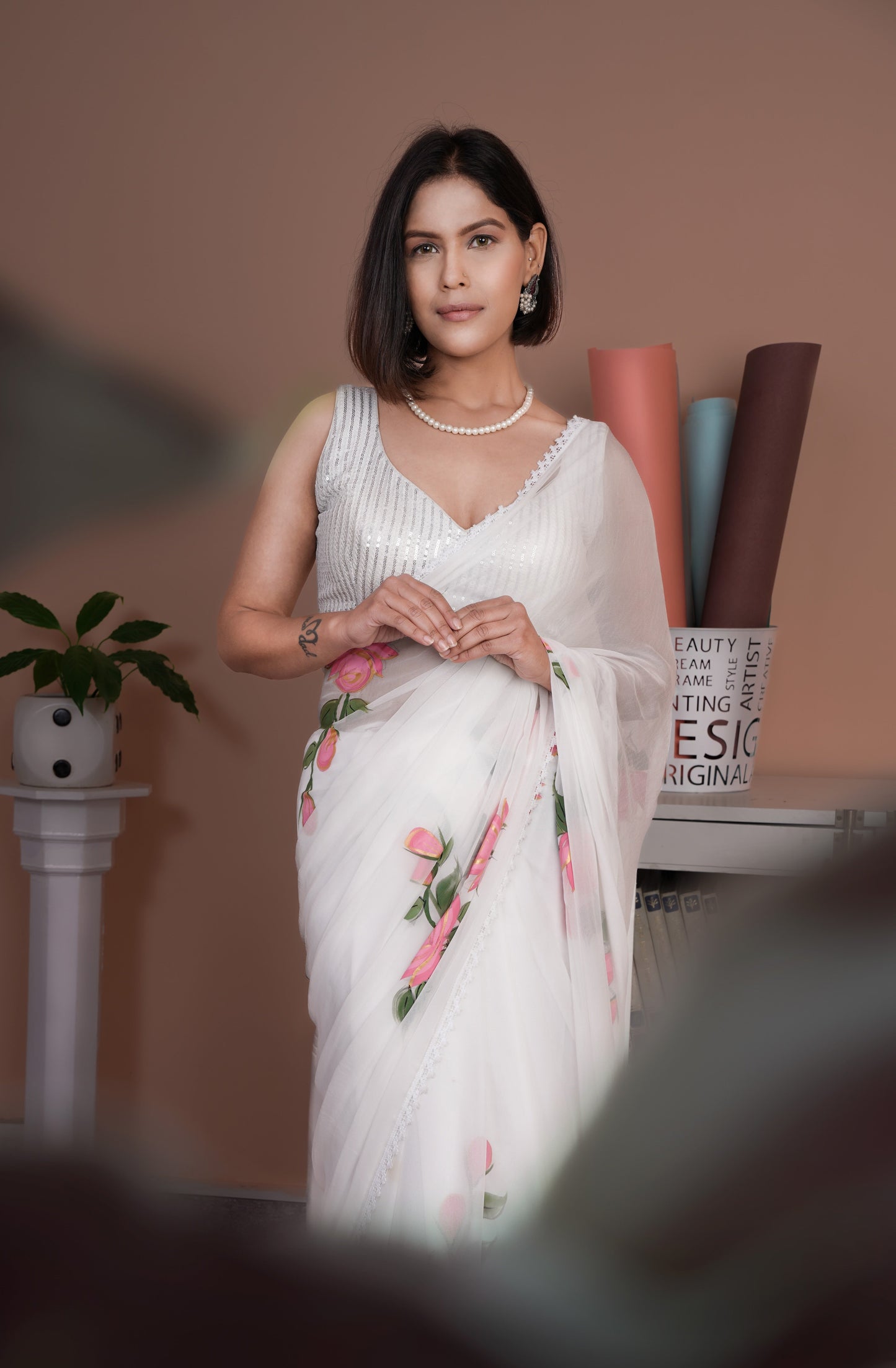 Elegant woman wearing a white saree with pink floral print, showcasing a sophisticated style with a lightweight design