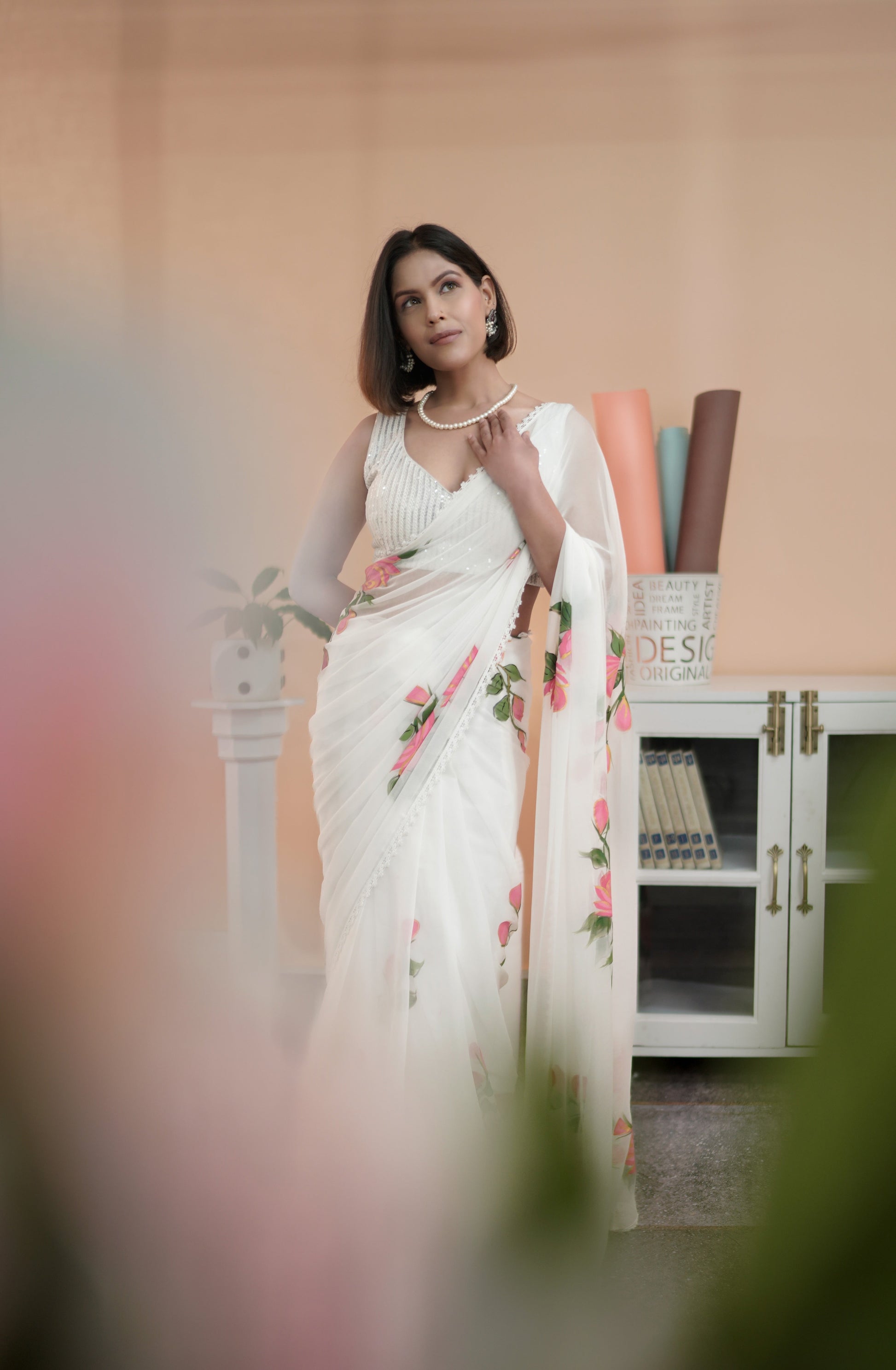Elegant model showcasing a white saree with pink floral print, perfect for festive occasions