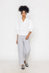 Stylera white v-neck blouse for women with three-quarter puff sleeves worn with gray pants