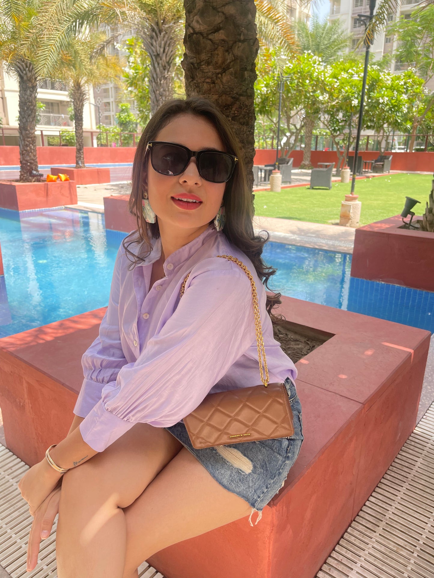 Model wearing a women's lightweight linen shirt in lavender shade with sunglasses and denim shorts