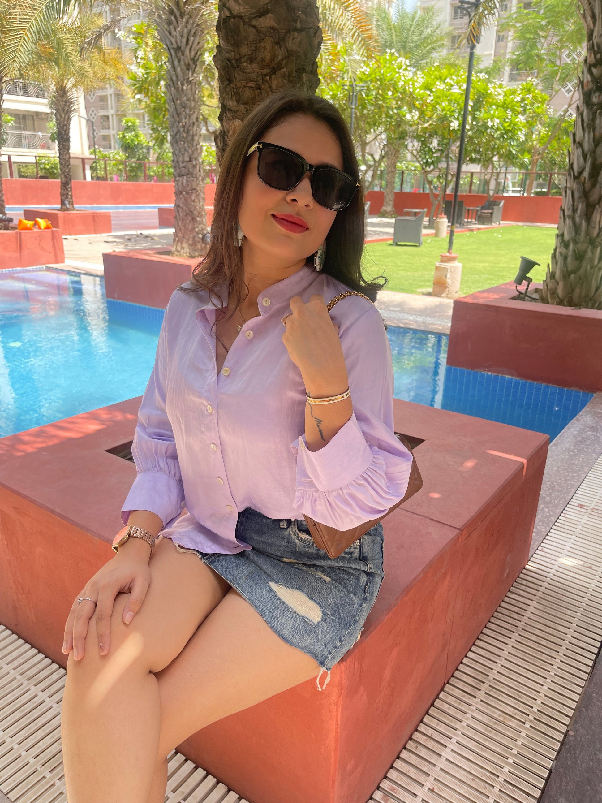 Model wearing a women's lightweight linen shirt in lavender, paired with a denim skirt by a poolside