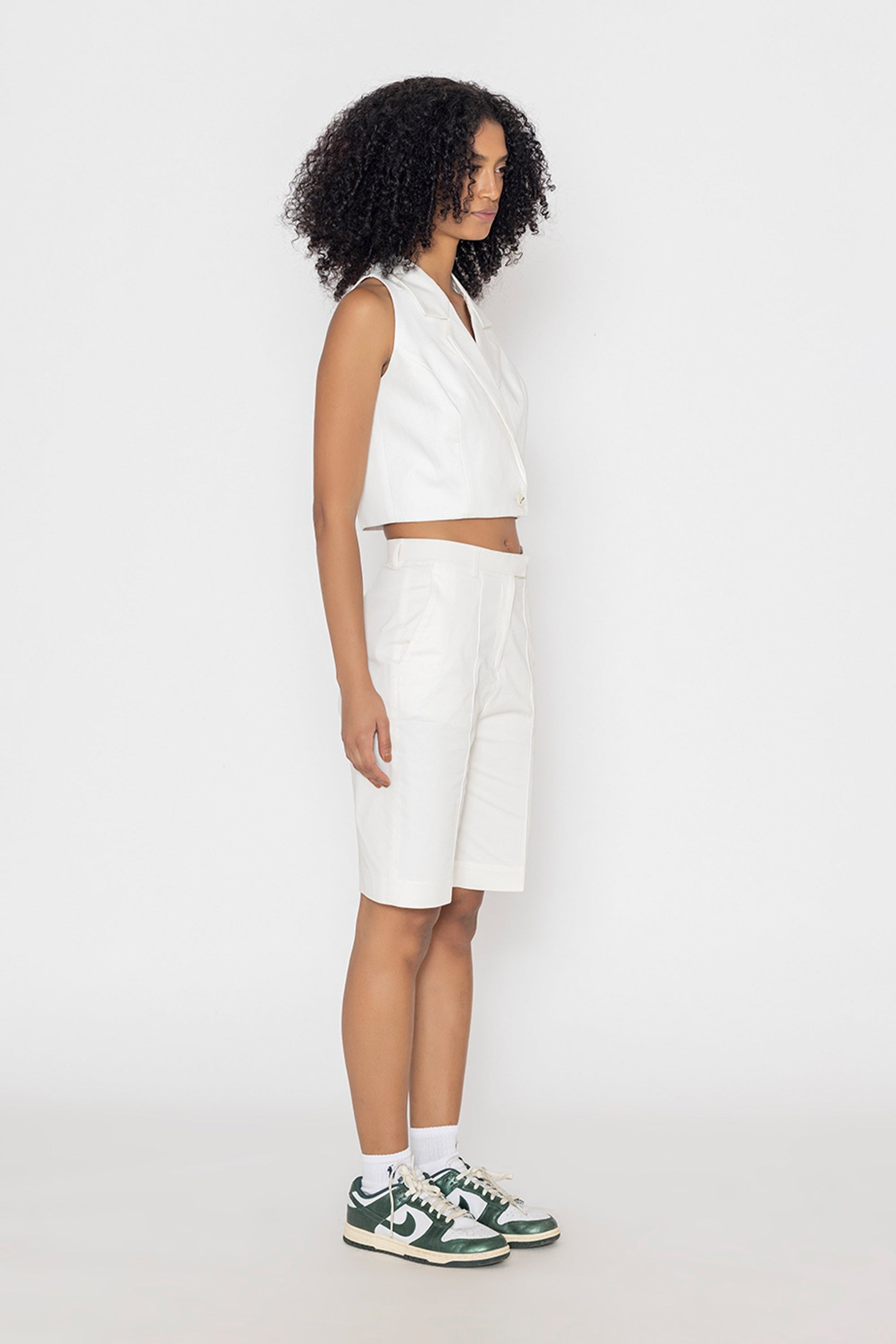 Model wearing Stylera women's white vest top paired with white shorts and sneakers