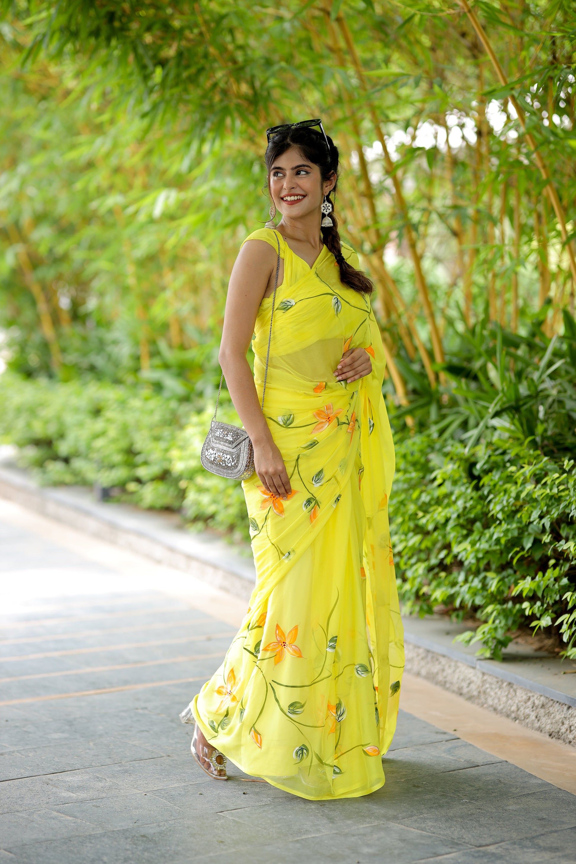 Stylera yellow saree with floral print, gracefully worn in a lush garden setting