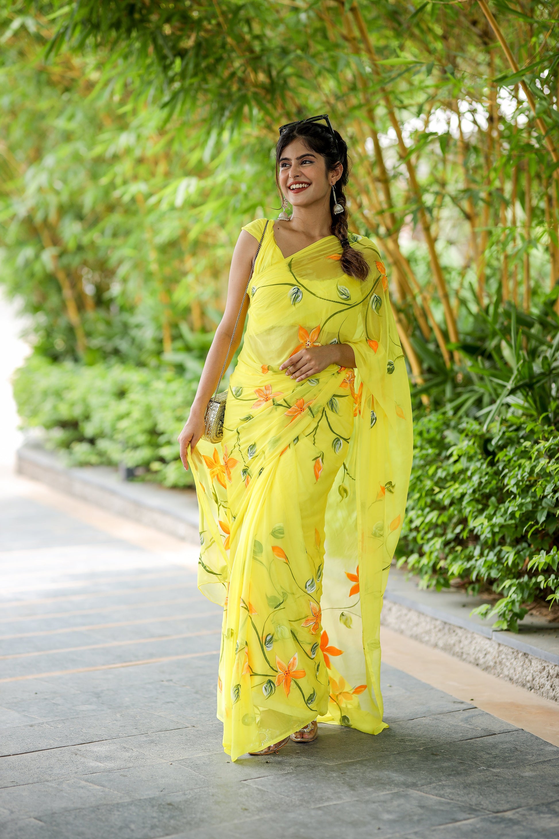 Elegant yellow saree with floral print, perfect for festive occasions, modeled in a lush garden setting