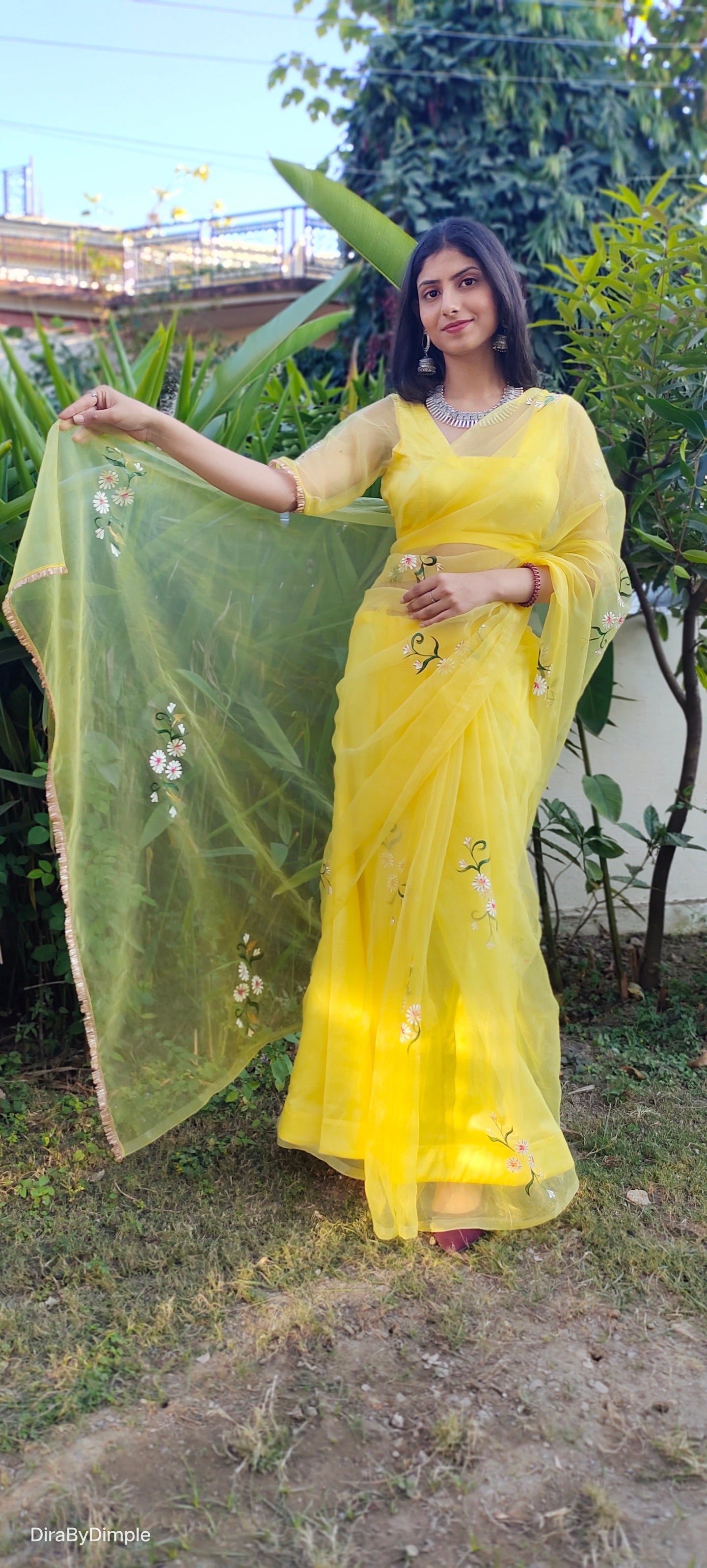 Model showcasing a yellow sunflower saree with floral embroidery and a flowing dupatta outdoors
