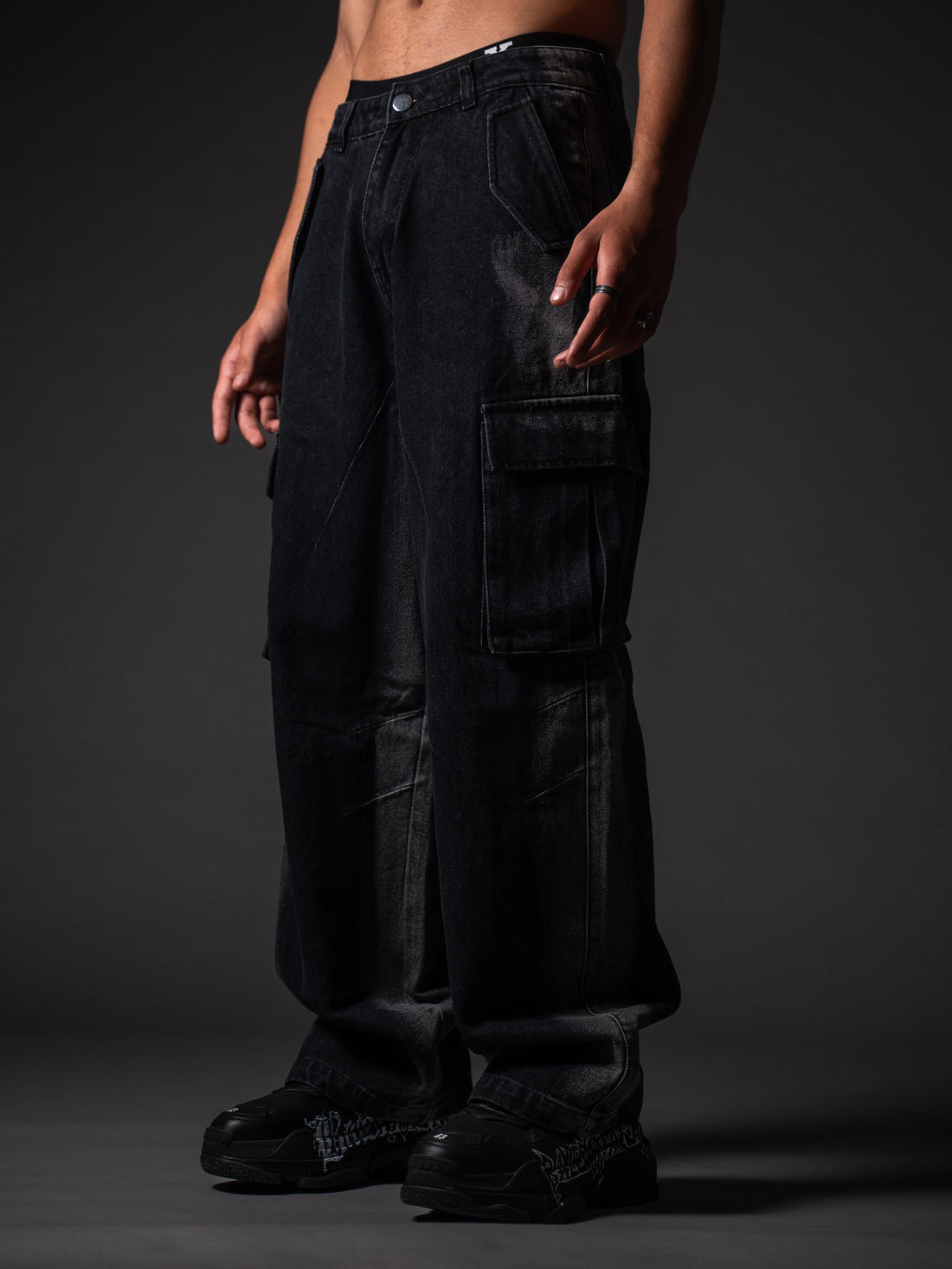 Man wearing black baggy denim cargo pants with flap pockets and chunky sneakers, Indian streetwear 2026.