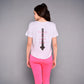 Wearing the 'Pilates Has Your Back' Printed Tee, this woman sports pink leggings and a white cotton-modal shirt with a spine graphic—an ideal motivational top for her next workout.